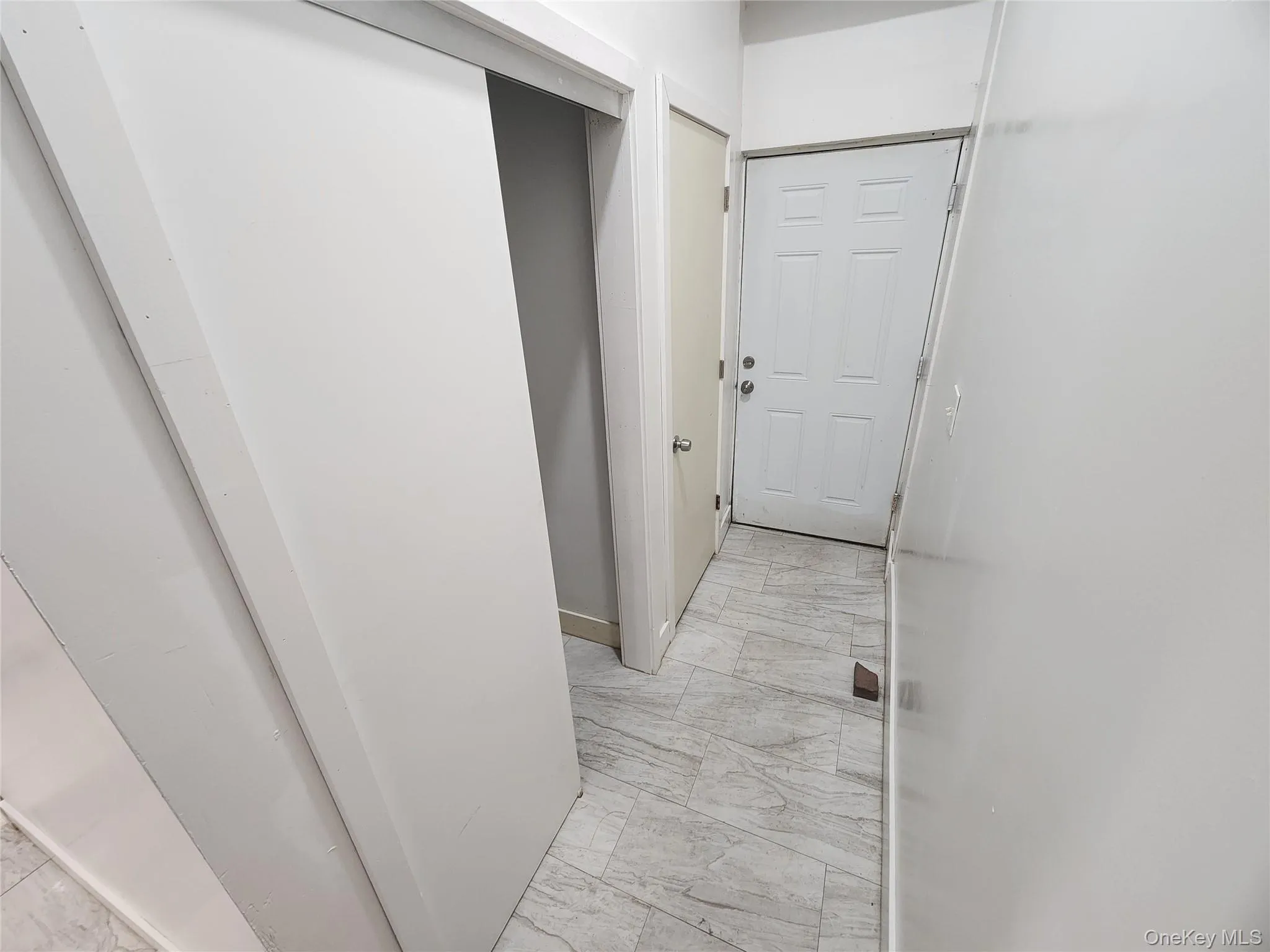 Hallway featuring light marble finish floors and baseboards Hallway featuring light marble finish floors and baseboards