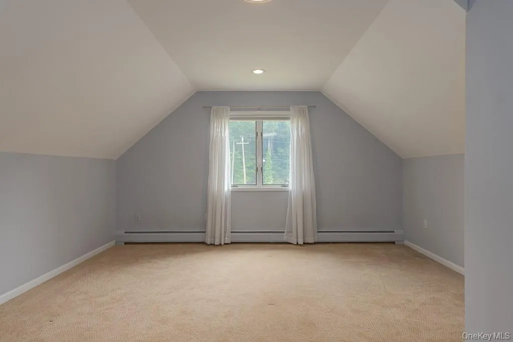Additional living space with light colored carpet, lofted ceiling, baseboard heating, and recessed lighting Additional living space with light colored carpet, lofted ceiling, baseboard heating, and recessed lighting