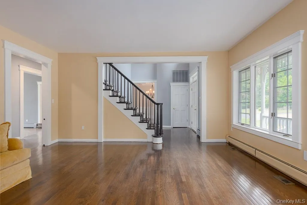 Foyer entrance with dark wood-style flooring, baseboard heating, stairway, and a chandelier Foyer entrance with dark wood-style flooring, baseboard heating, stairway, and a chandelier