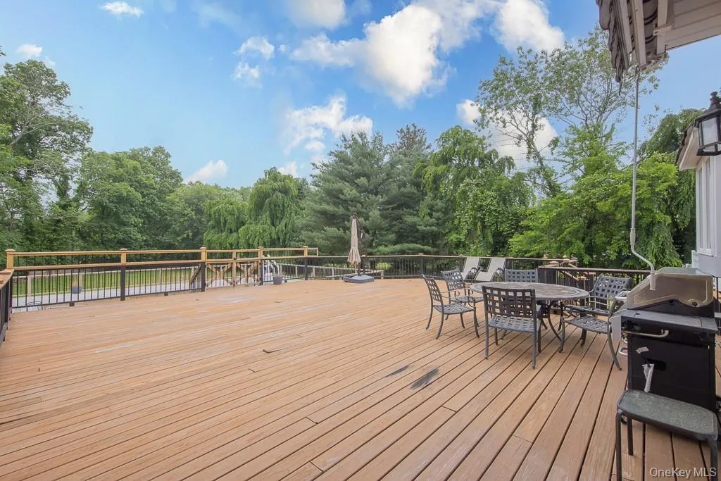 Deck with a grill, outdoor dining space, and view of scattered trees Deck with a grill, outdoor dining space, and view of scattered trees