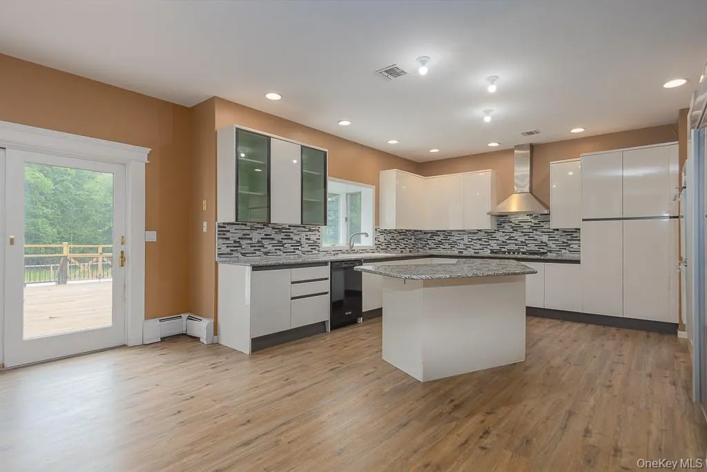 Kitchen featuring white cabinetry, glass insert cabinets, light wood-style flooring, backsplash, and recessed lighting Kitchen featuring white cabinetry, glass insert cabinets, light wood-style flooring, backsplash, and recessed lighting