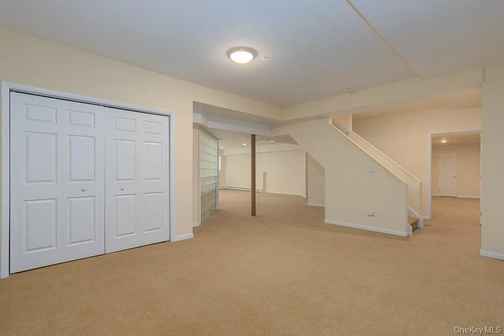 Finished below grade area with stairway and light colored carpet Finished below grade area with stairway and light colored carpet