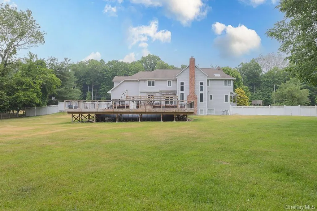 Rear view of house featuring a deck and a chimney Rear view of house featuring a deck and a chimney