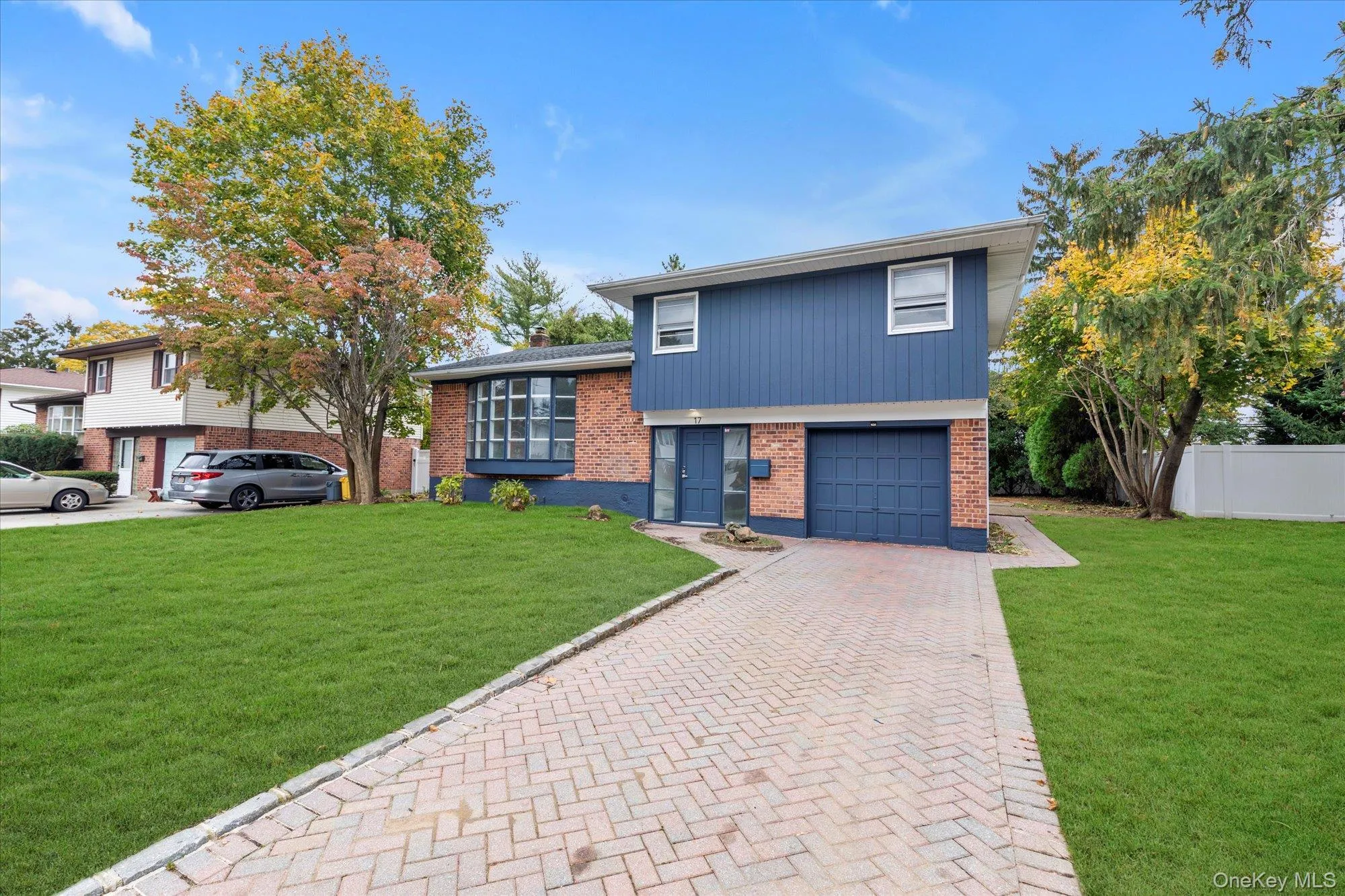 Tri-level home with brick siding, an attached garage, and decorative driveway Tri-level home with brick siding, an attached garage, and decorative driveway