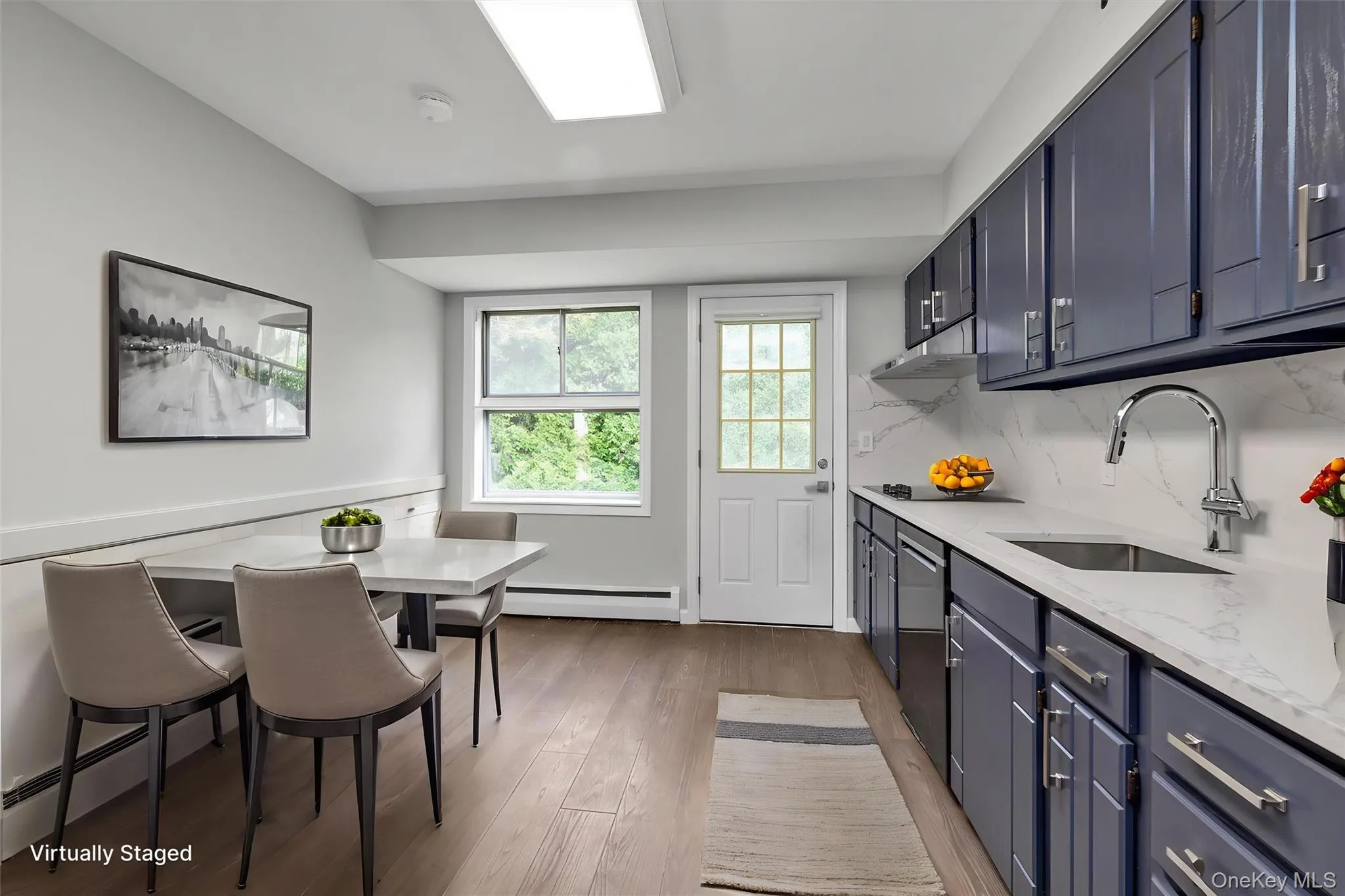 Kitchen with blue cabinets, light stone counters, light wood-style floors, dishwasher, and a baseboard heating unit Kitchen with blue cabinets, light stone counters, light wood-style floors, dishwasher, and a baseboard heating unit