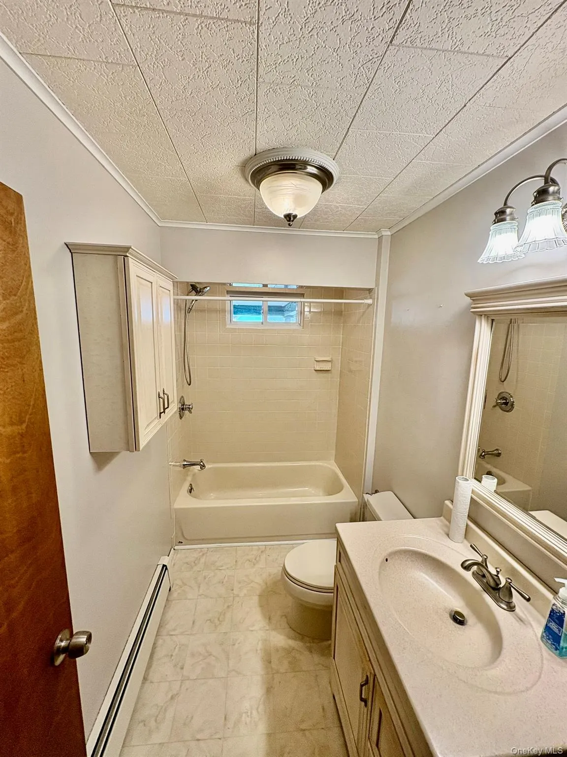 Bathroom with shower / bathtub combination, a baseboard heating unit, vanity, and crown molding Bathroom with shower / bathtub combination, a baseboard heating unit, vanity, and crown molding