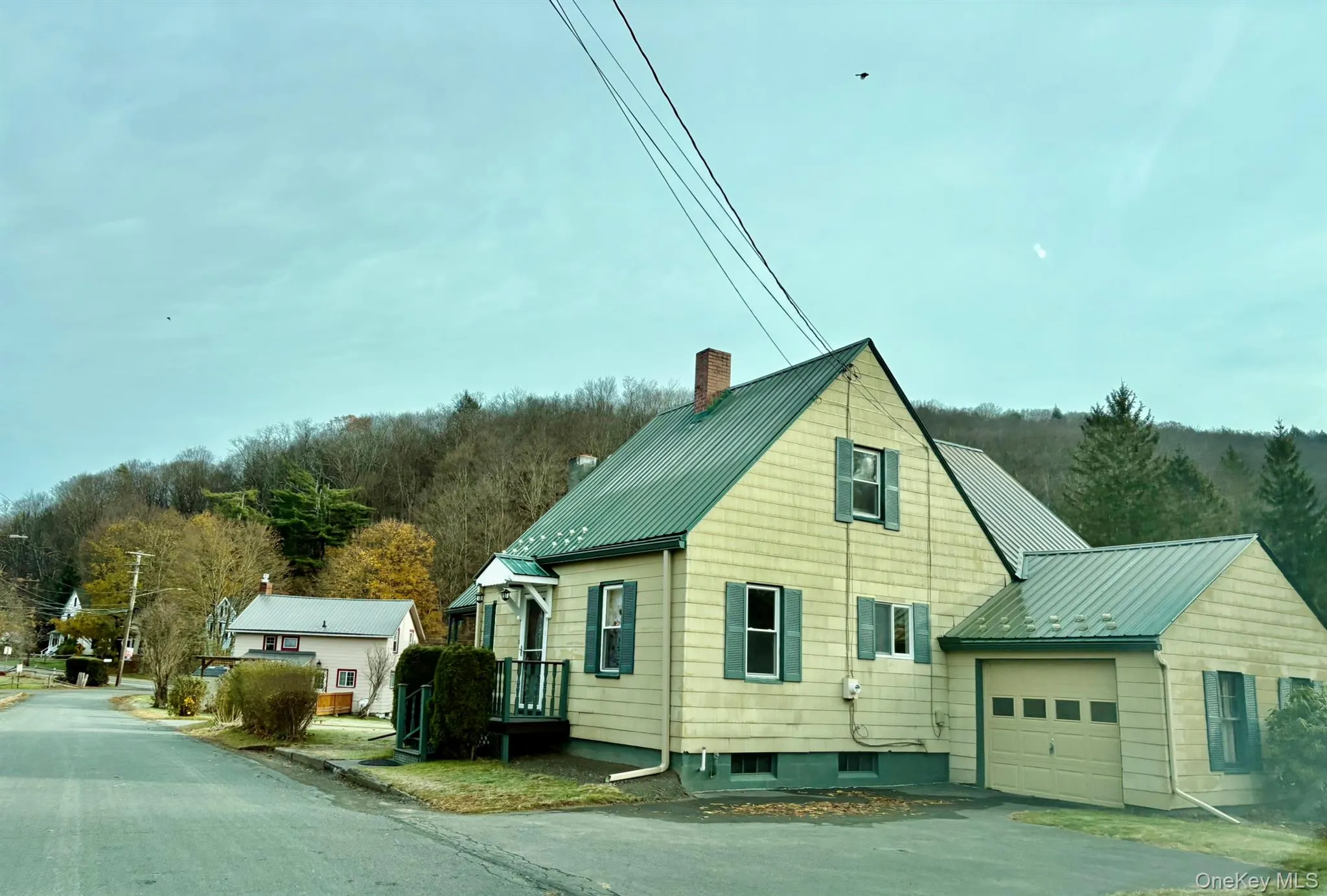 View of home's exterior with a metal roof, a chimney, driveway, a garage, and a standing seam roof View of home's exterior with a metal roof, a chimney, driveway, a garage, and a standing seam roof