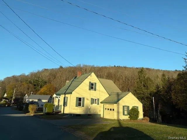View of front of home featuring a view of trees, a garage, a chimney, and driveway View of front of home featuring a view of trees, a garage, a chimney, and driveway