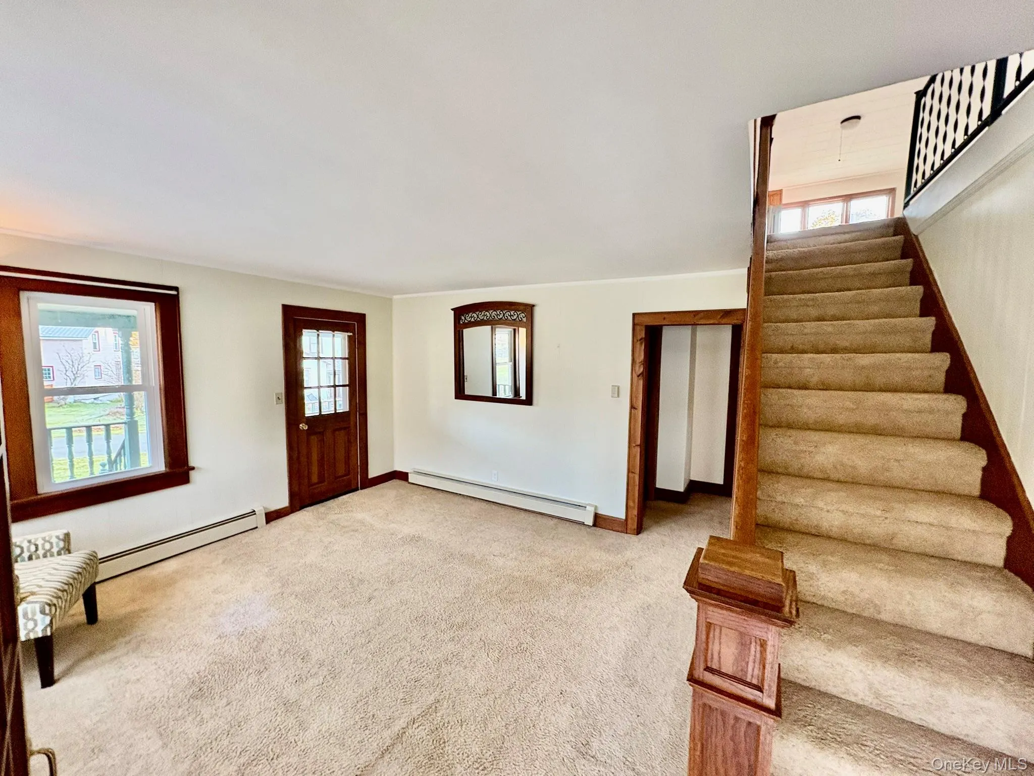 Foyer featuring a baseboard radiator, carpet flooring, and stairway Foyer featuring a baseboard radiator, carpet flooring, and stairway