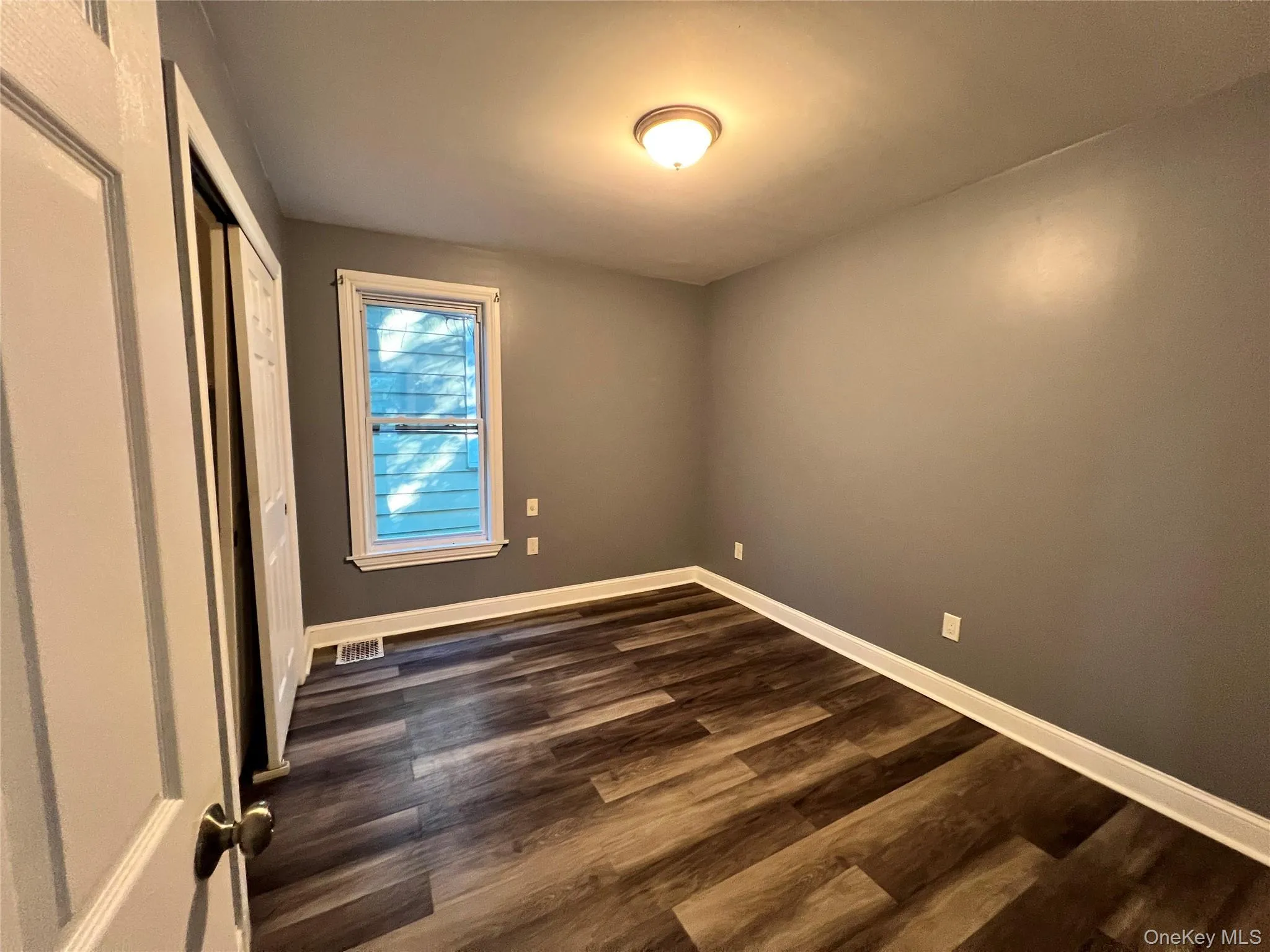 Unfurnished bedroom with dark wood-style floors and a closet Unfurnished bedroom with dark wood-style floors and a closet