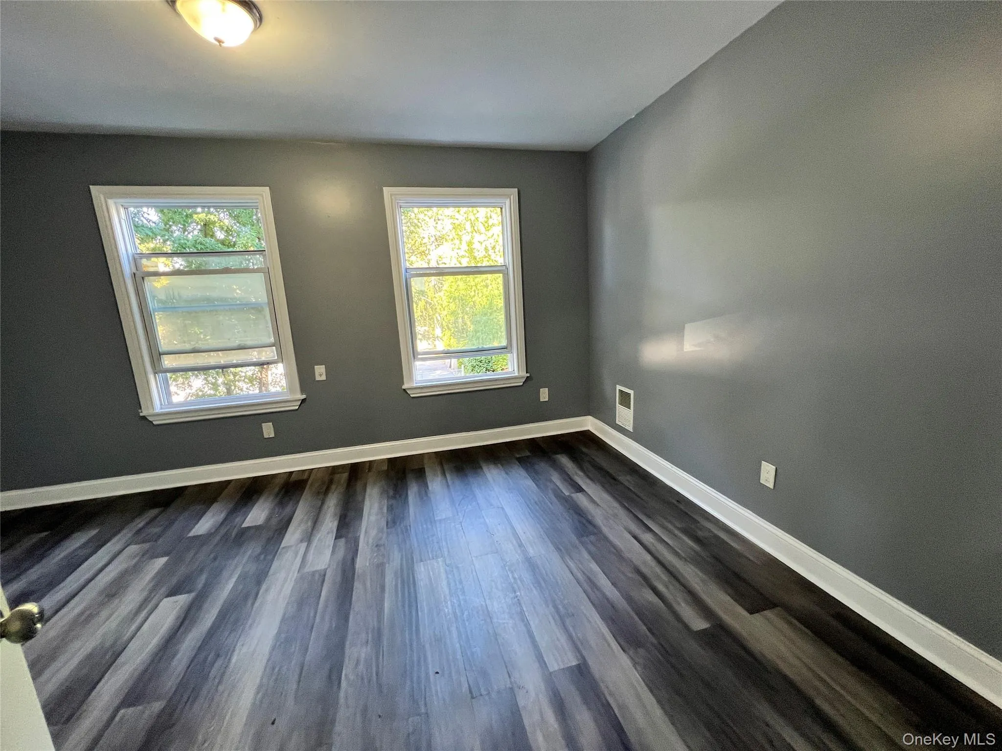 Empty room with plenty of natural light and dark wood finished floors Empty room with plenty of natural light and dark wood finished floors