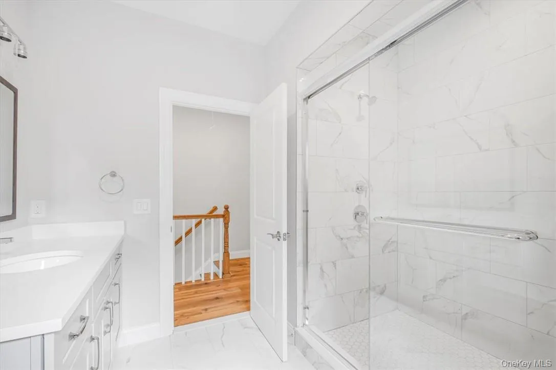 Bathroom featuring vanity, a shower with shower door, and hardwood / wood-style floors Bathroom featuring vanity, a shower with shower door, and hardwood / wood-style floors