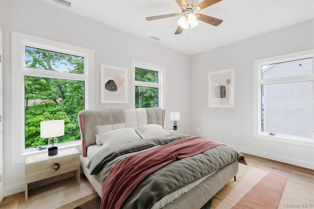 Bedroom featuring ceiling fan, light wood-type flooring, and multiple windows *Virtually Staged Bedroom featuring ceiling fan, light wood-type flooring, and multiple windows *Virtually Staged