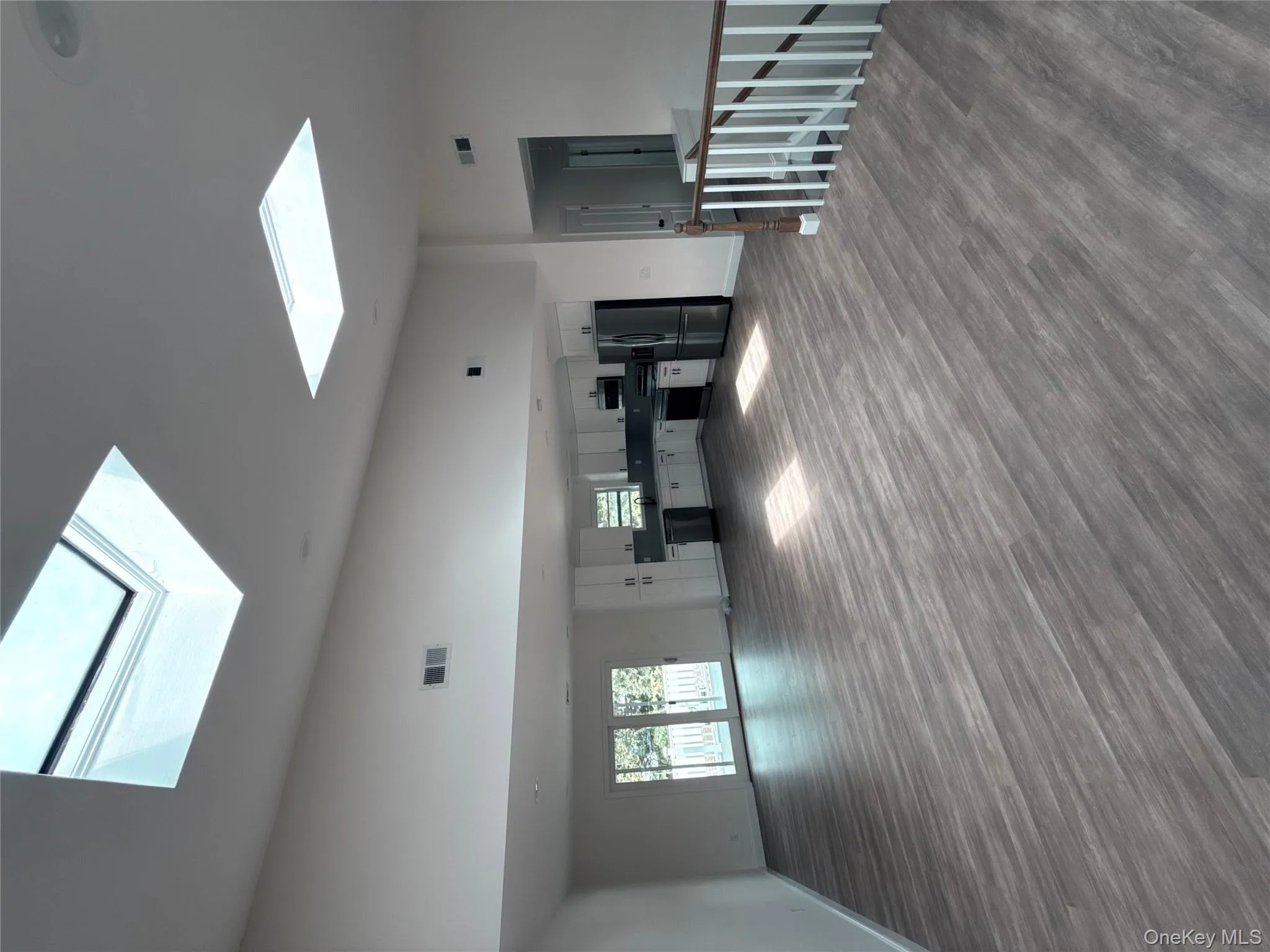 Unfurnished living room featuring dark wood-style flooring, high vaulted ceiling, and a skylight Unfurnished living room featuring dark wood-style flooring, high vaulted ceiling, and a skylight