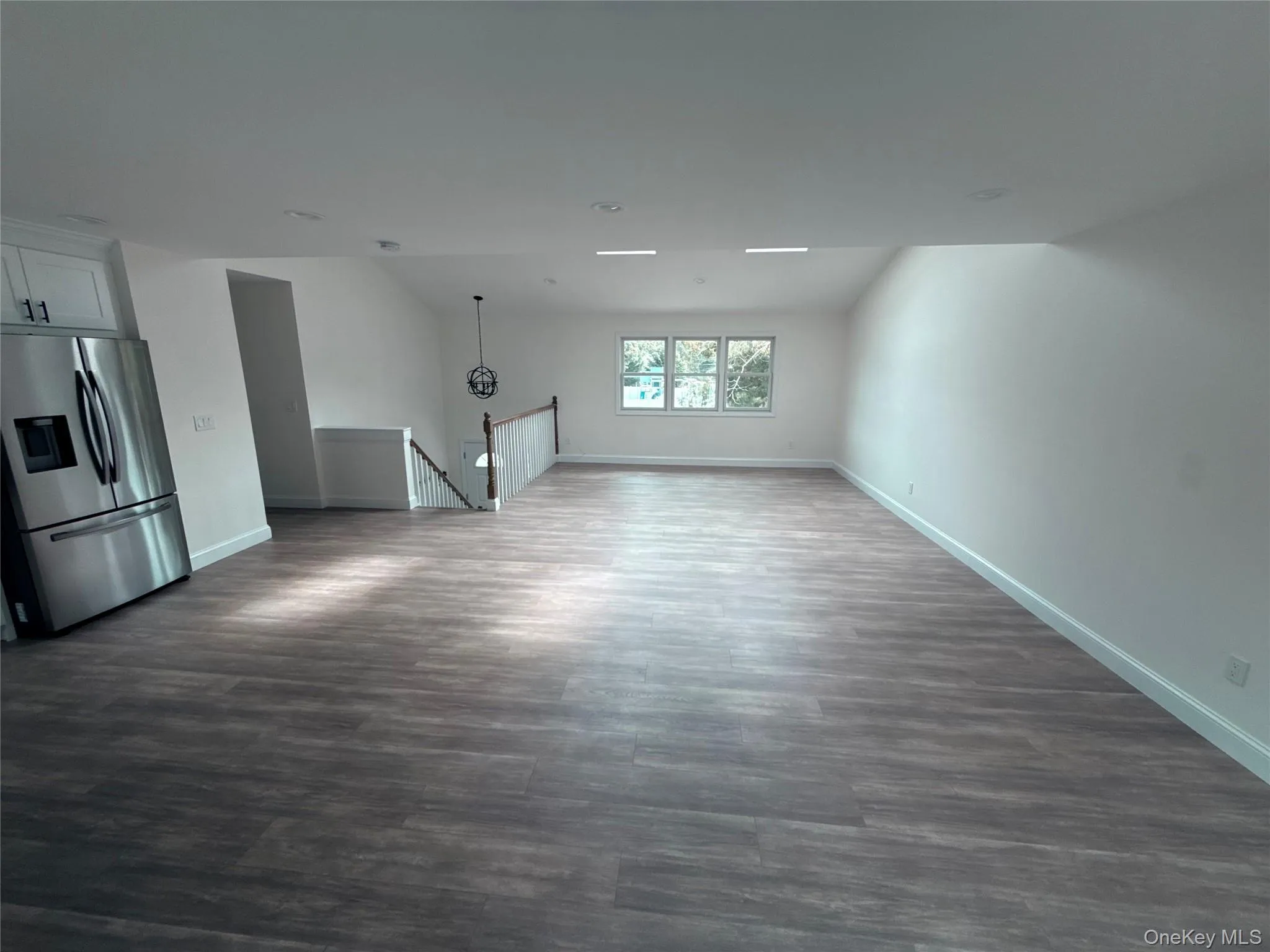 Unfurnished living room with dark wood-style flooring and lofted ceiling Unfurnished living room with dark wood-style flooring and lofted ceiling