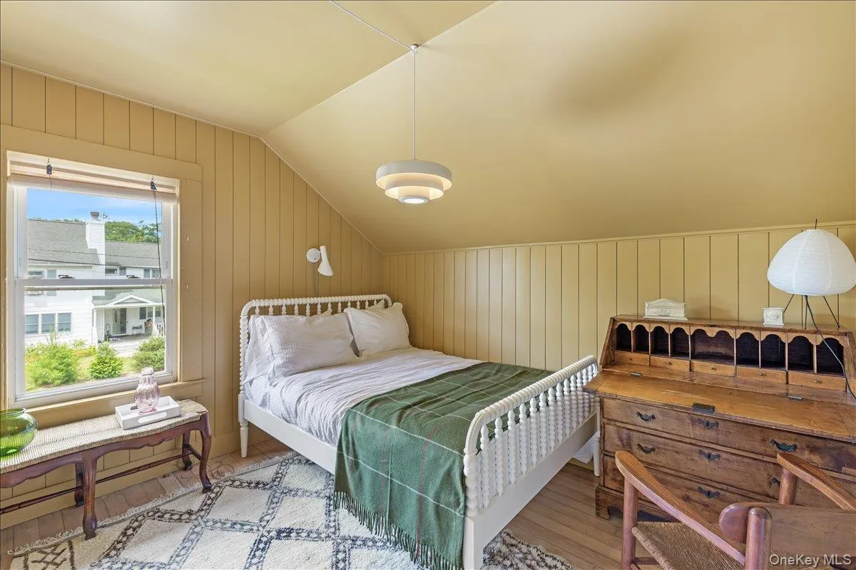 Bedroom with wood walls, vaulted ceiling, and wood finished floors Bedroom with wood walls, vaulted ceiling, and wood finished floors