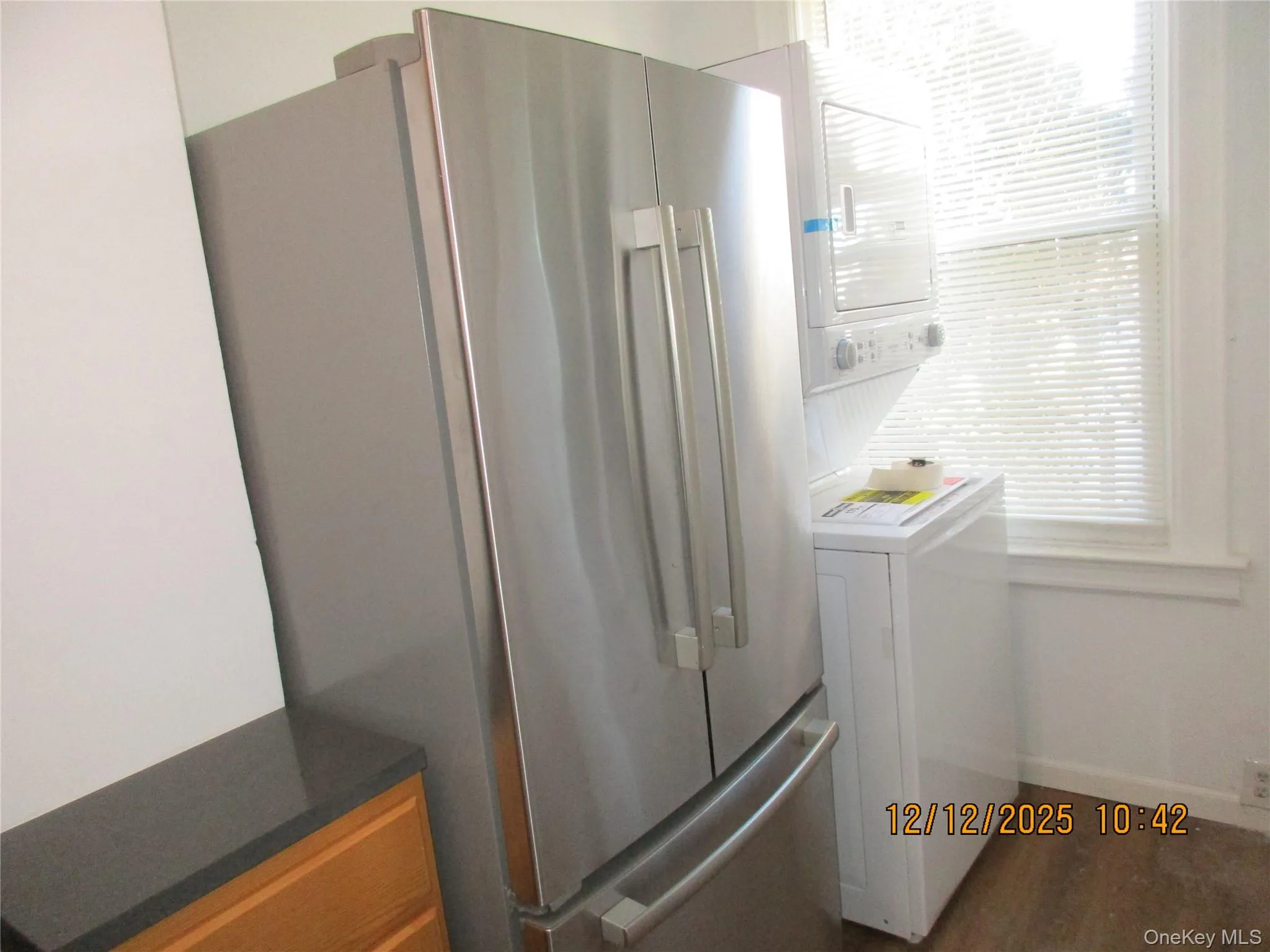 Washroom with healthy amount of natural light, stacked washer and clothes dryer, and wood finished floors Washroom with healthy amount of natural light, stacked washer and clothes dryer, and wood finished floors