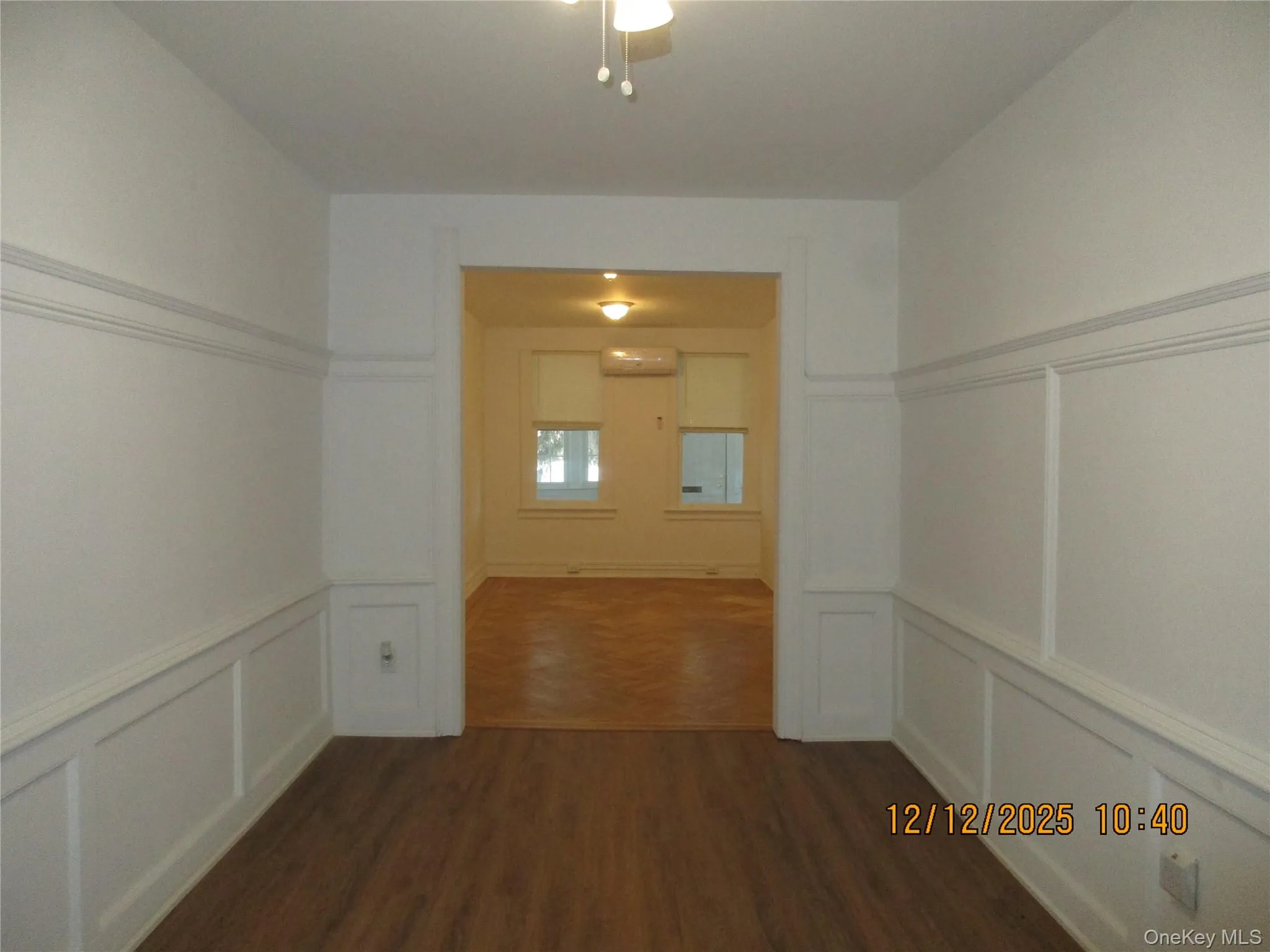 Corridor with a decorative wall, a wainscoted wall, dark wood finished floors, and a wall mounted air conditioner Corridor with a decorative wall, a wainscoted wall, dark wood finished floors, and a wall mounted air conditioner