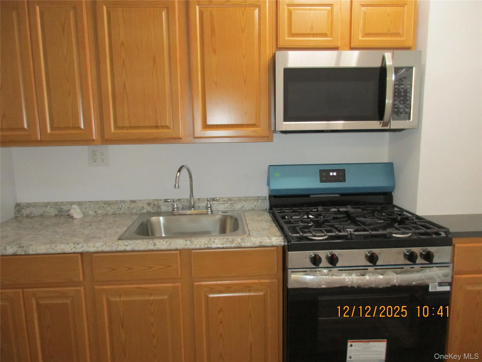 Kitchen with stainless steel appliances, light countertops, and brown cabinetry Kitchen with stainless steel appliances, light countertops, and brown cabinetry