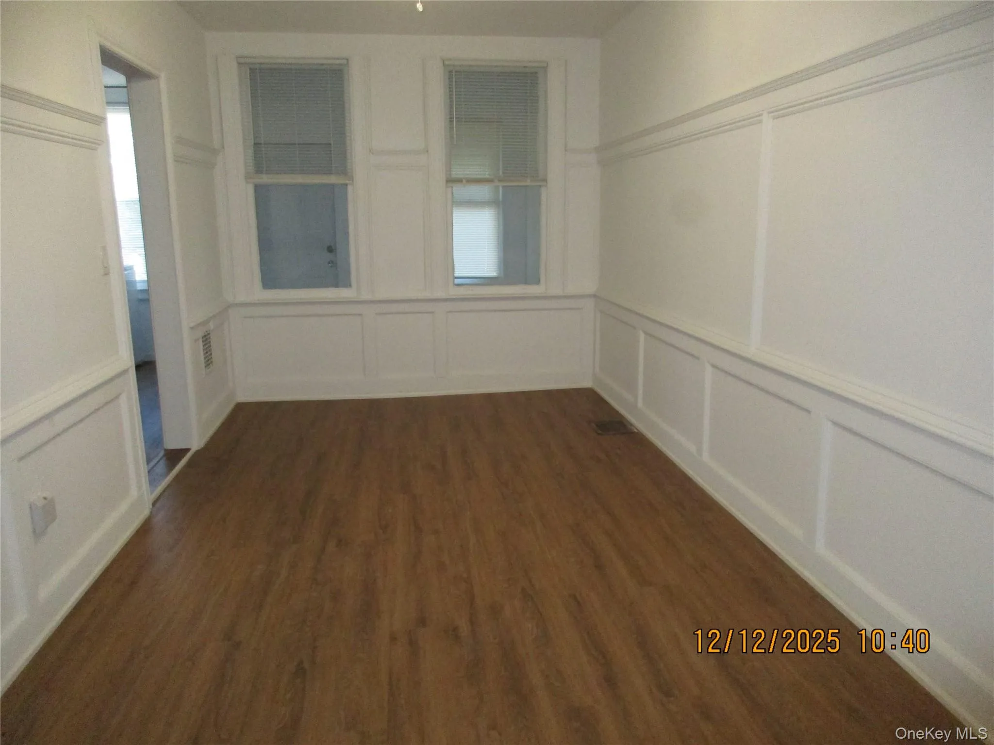 Unfurnished room with a decorative wall, wainscoting, and dark wood finished floors Unfurnished room with a decorative wall, wainscoting, and dark wood finished floors