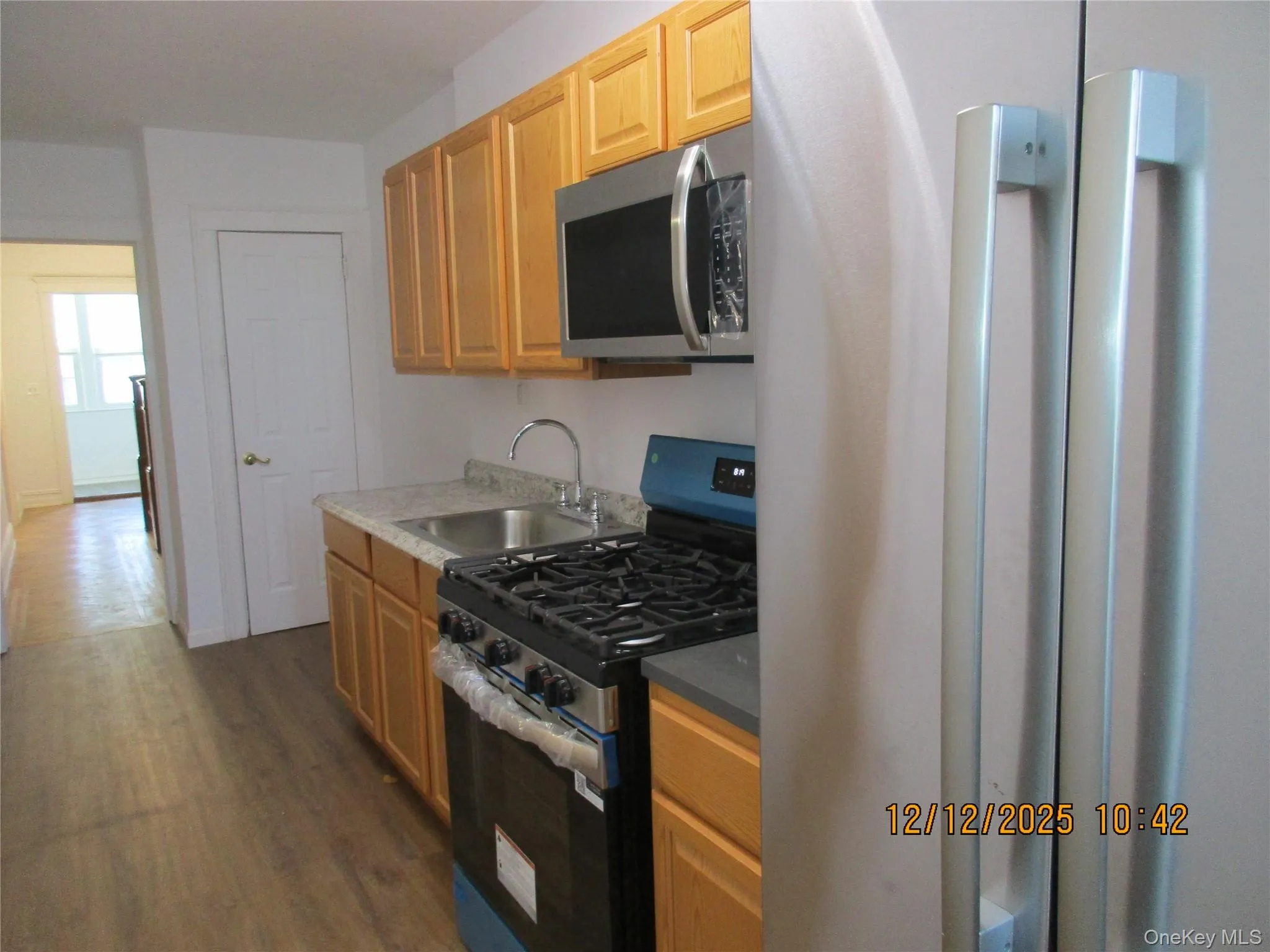 Kitchen featuring stainless steel appliances, dark wood-style flooring, and light brown cabinetry Kitchen featuring stainless steel appliances, dark wood-style flooring, and light brown cabinetry