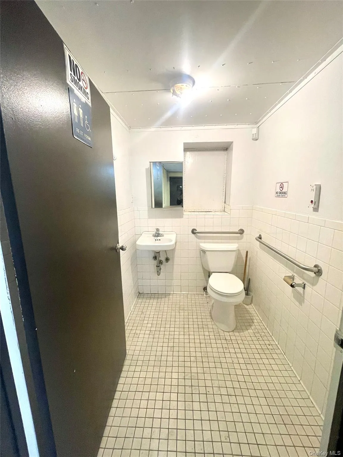Bathroom featuring tile walls, tile patterned flooring, wainscoting, and ornamental molding Bathroom featuring tile walls, tile patterned flooring, wainscoting, and ornamental molding
