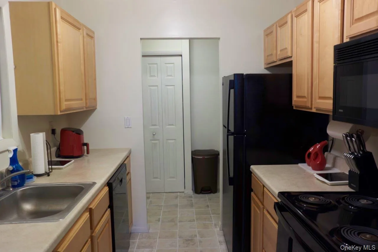 Kitchen featuring light brown cabinets, light countertops, and black appliances Kitchen featuring light brown cabinets, light countertops, and black appliances
