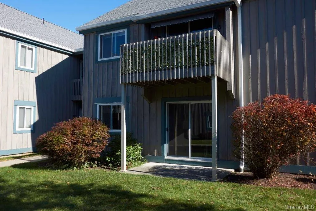 Rear view of house with a patio, a balcony, roof with shingles, and board and batten siding Rear view of house with a patio, a balcony, roof with shingles, and board and batten siding