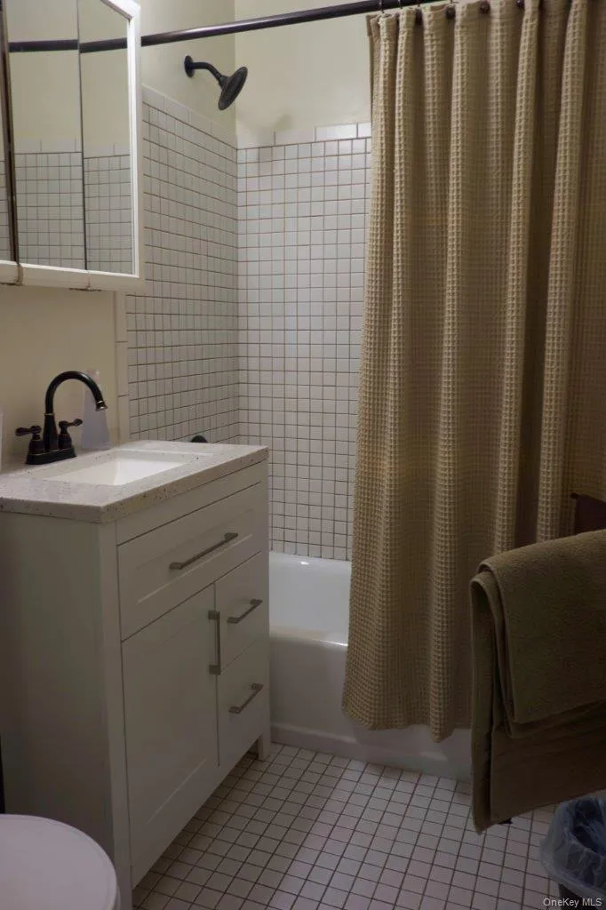 Bathroom featuring shower / tub combo, vanity, and light tile patterned floors Bathroom featuring shower / tub combo, vanity, and light tile patterned floors