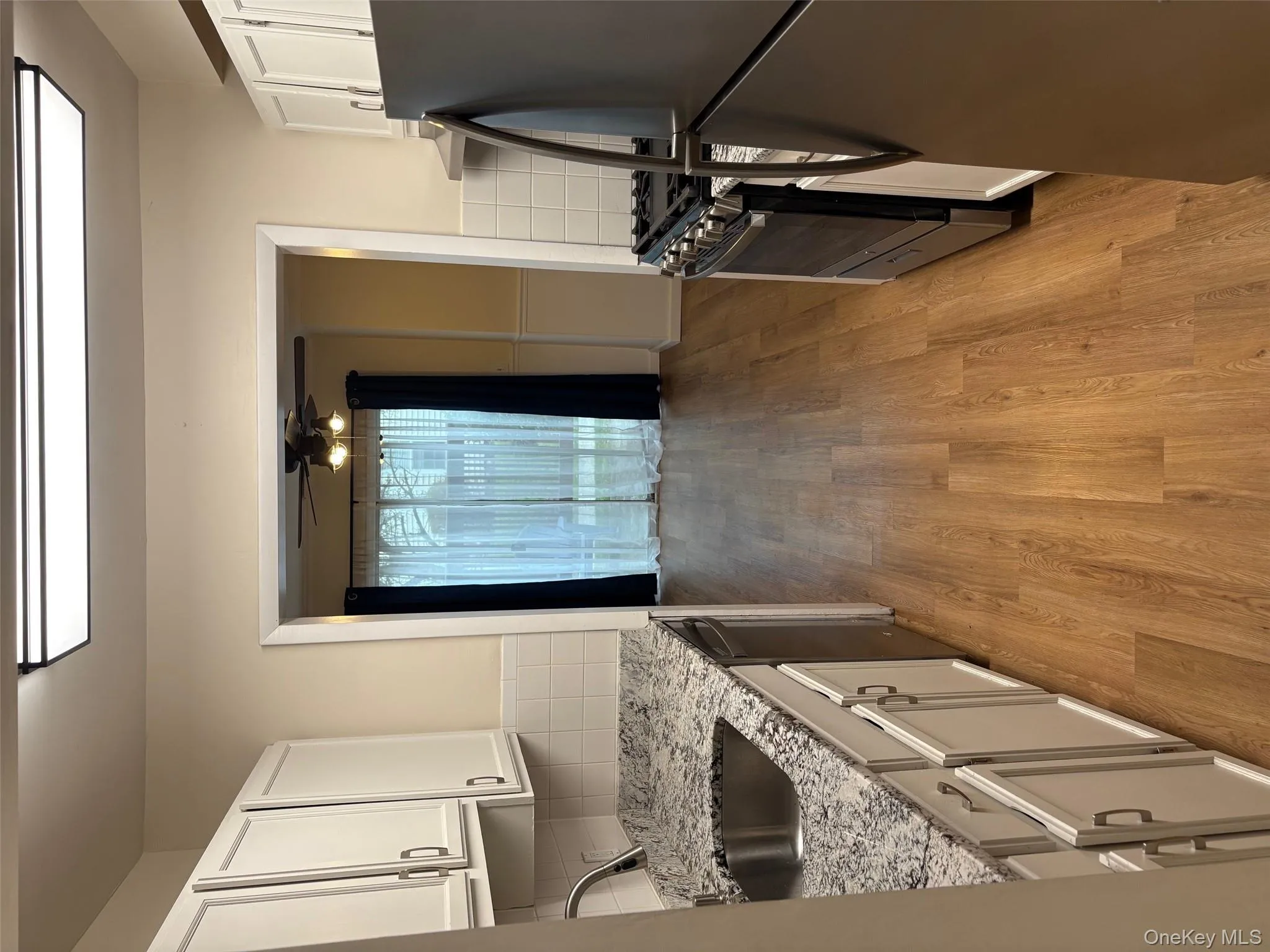 Kitchen featuring stainless steel appliances, ceiling fan, light wood-style floors, white cabinets, and light stone counters Kitchen featuring stainless steel appliances, ceiling fan, light wood-style floors, white cabinets, and light stone counters