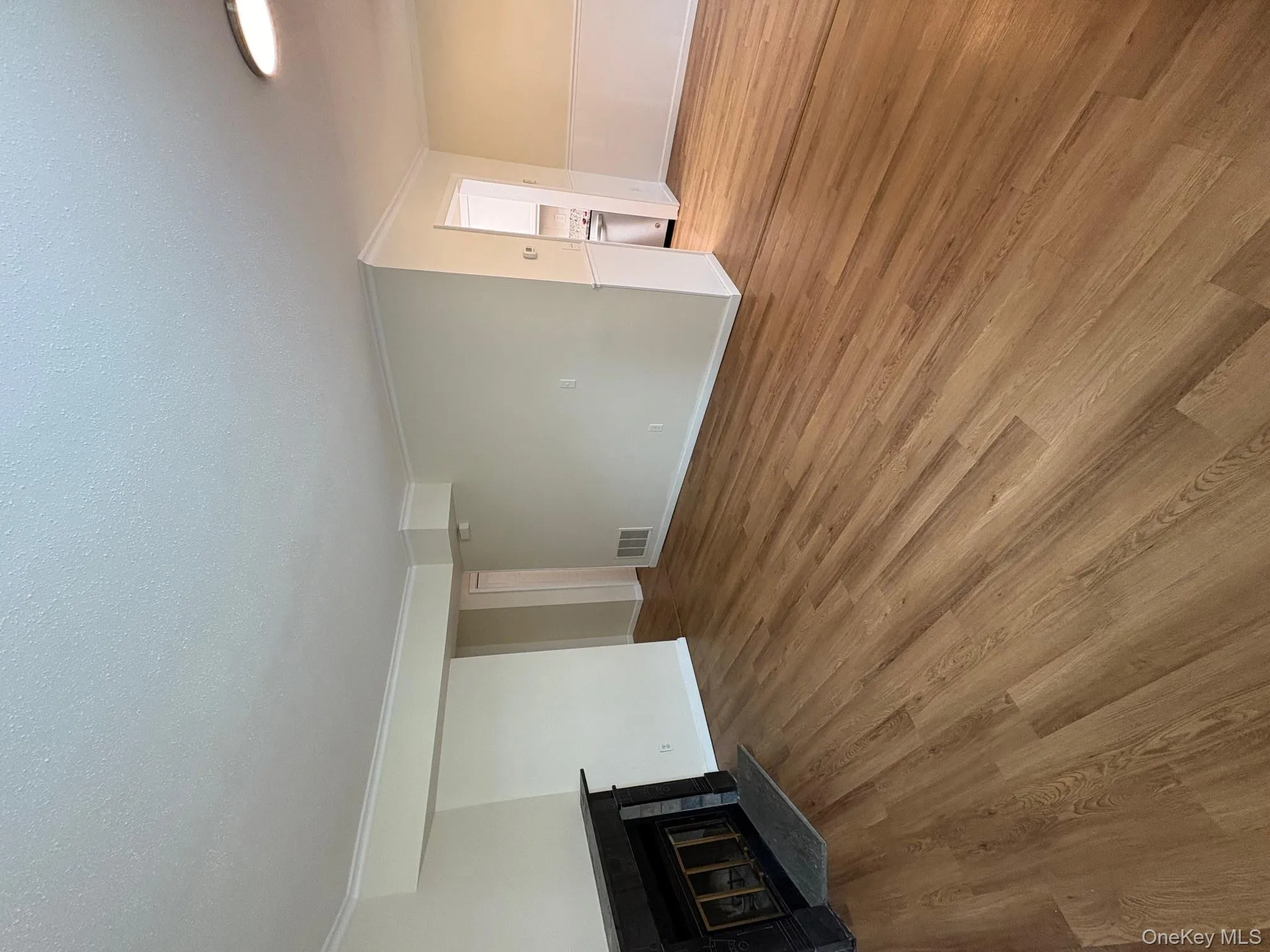 Unfurnished living room featuring light wood-style flooring, ornamental molding, a glass covered fireplace, and a textured ceiling Unfurnished living room featuring light wood-style flooring, ornamental molding, a glass covered fireplace, and a textured ceiling