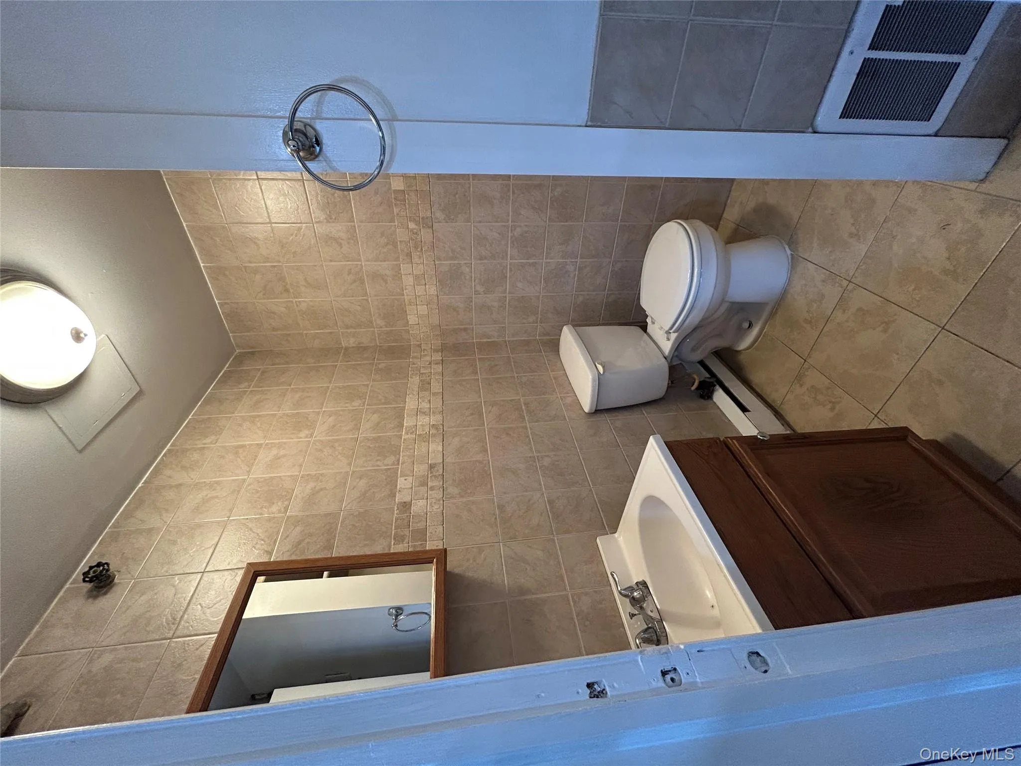 Bathroom featuring tile walls, light tile patterned flooring, vanity, and a baseboard radiator Bathroom featuring tile walls, light tile patterned flooring, vanity, and a baseboard radiator