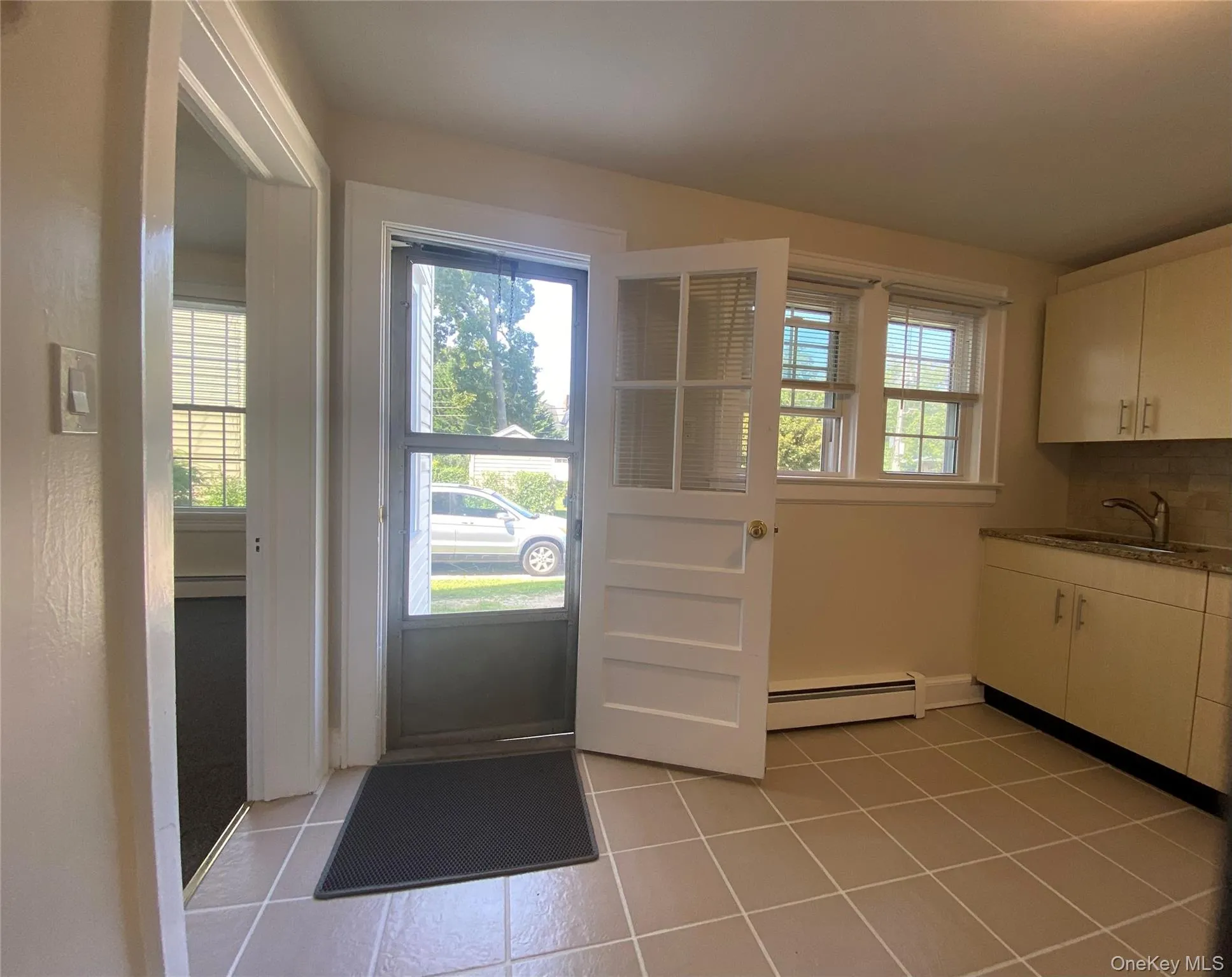Doorway to outside with tile patterned flooring and a baseboard heating unit Doorway to outside with tile patterned flooring and a baseboard heating unit