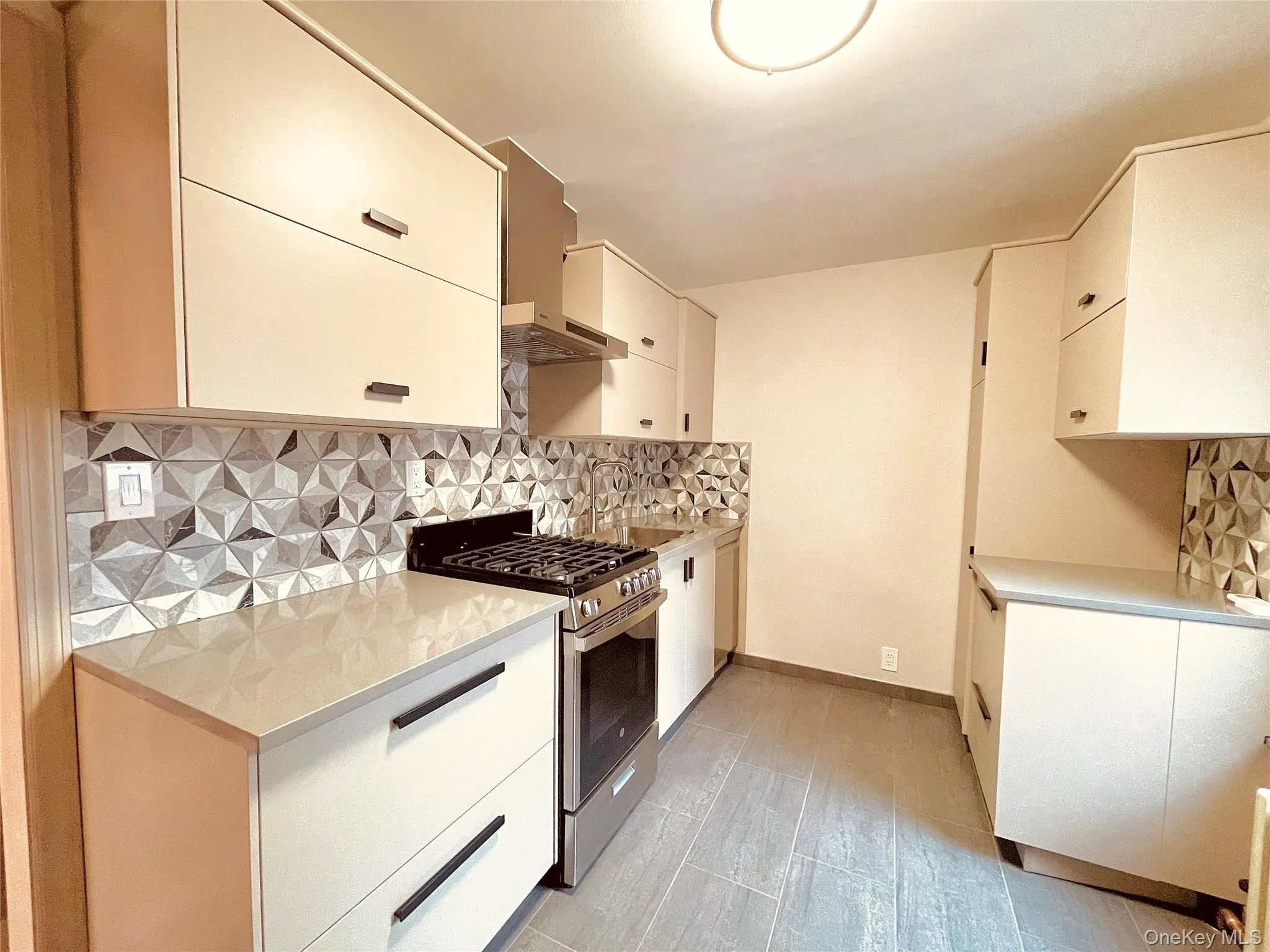 Kitchen with tasteful backsplash, stainless steel range with gas stovetop, light wood-style floors, wall chimney exhaust hood, and modern cabinets Kitchen with tasteful backsplash, stainless steel range with gas stovetop, light wood-style floors, wall chimney exhaust hood, and modern cabinets