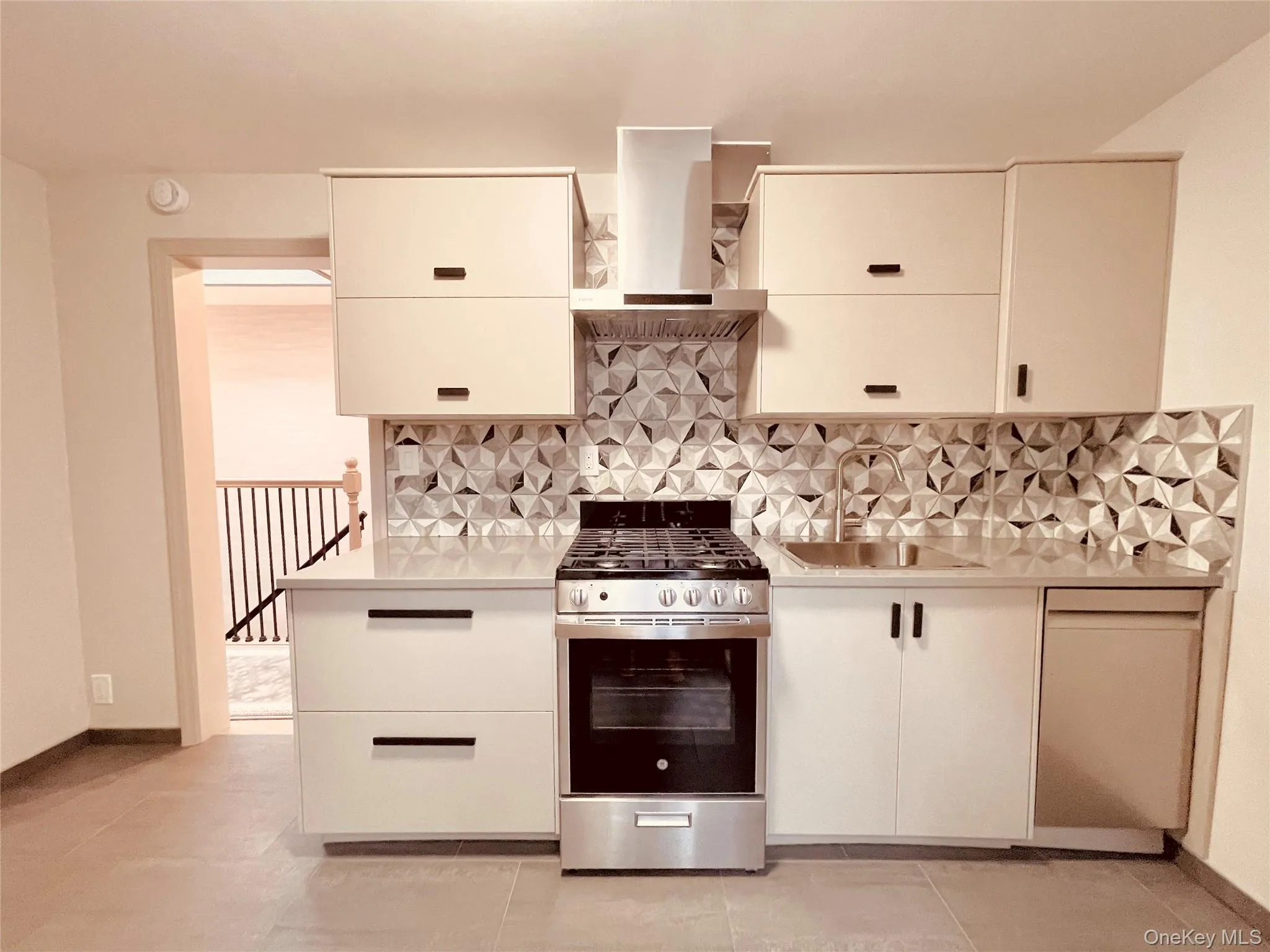Kitchen with gas stove, island exhaust hood, tasteful backsplash, light stone countertops, and light tile patterned floors Kitchen with gas stove, island exhaust hood, tasteful backsplash, light stone countertops, and light tile patterned floors