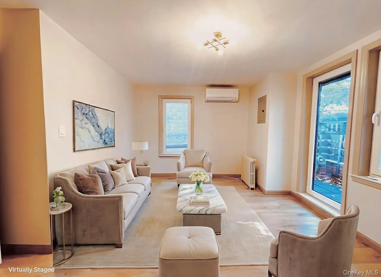 Living room with radiator, an AC wall unit, wood finished floors, and electric panel Living room with radiator, an AC wall unit, wood finished floors, and electric panel