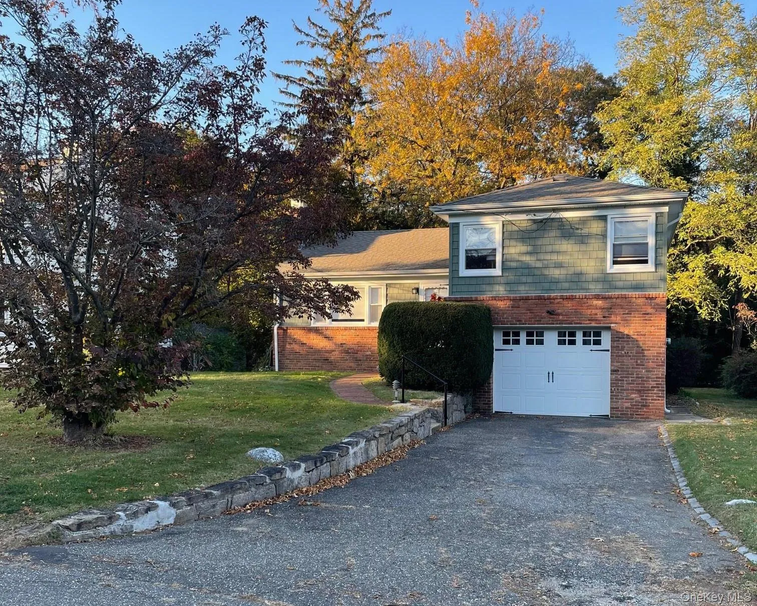 View of front of home with brick siding, asphalt driveway, a front yard, and a garage View of front of home with brick siding, asphalt driveway, a front yard, and a garage