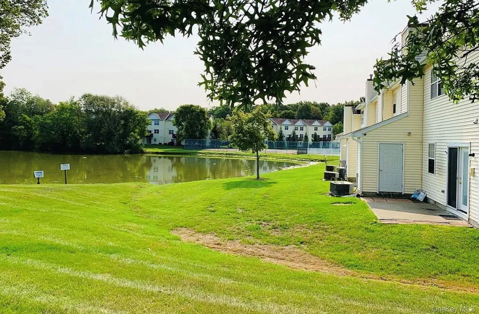 View of grassy yard featuring a water view and a patio View of grassy yard featuring a water view and a patio