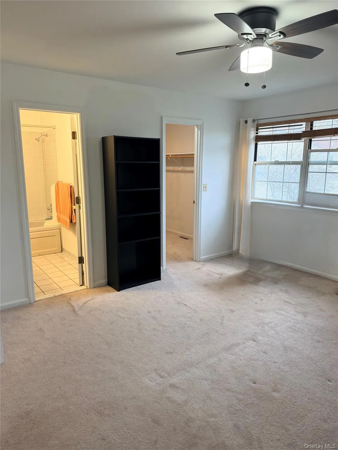 Unfurnished bedroom with a spacious closet, light colored carpet, a ceiling fan, and connected bathroom Unfurnished bedroom with a spacious closet, light colored carpet, a ceiling fan, and connected bathroom