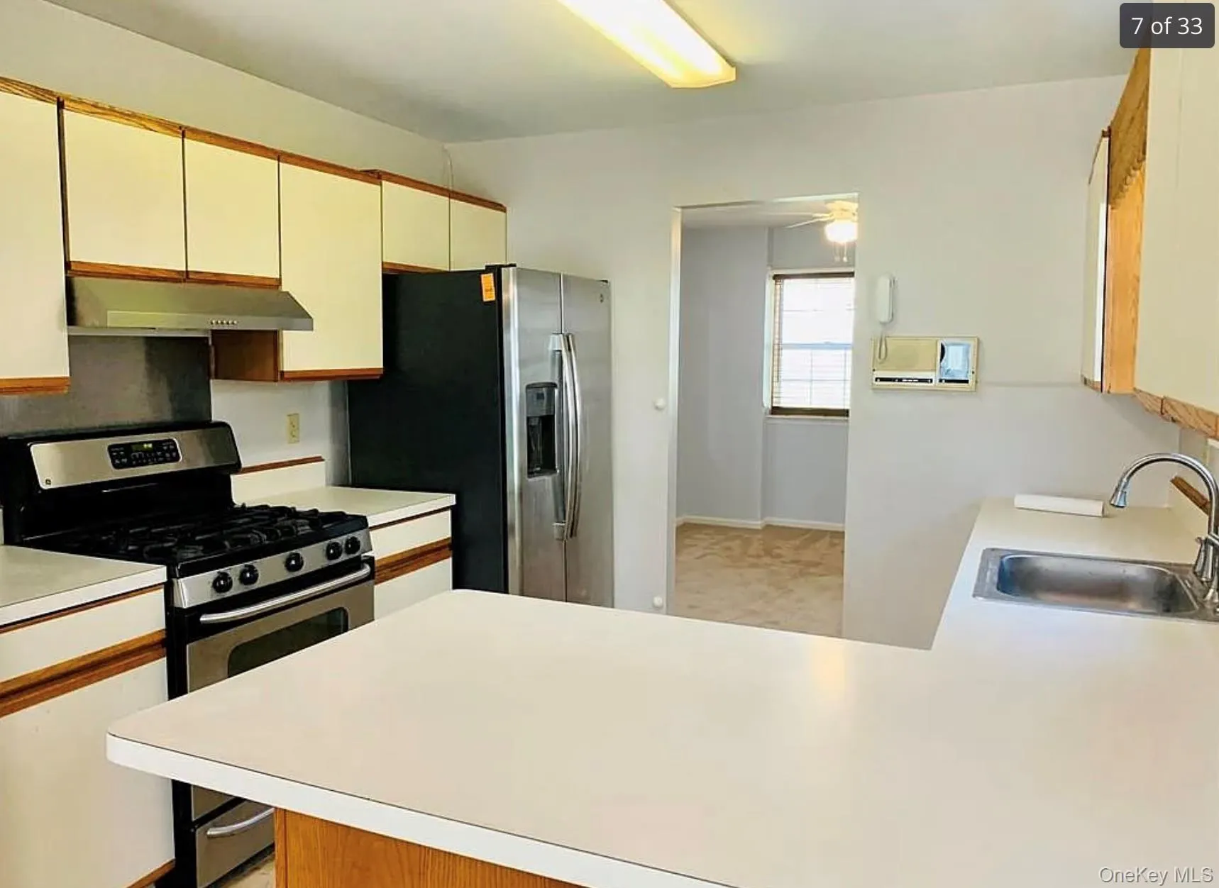 Kitchen with stainless steel appliances, light countertops, a peninsula, and brown cabinetry Kitchen with stainless steel appliances, light countertops, a peninsula, and brown cabinetry