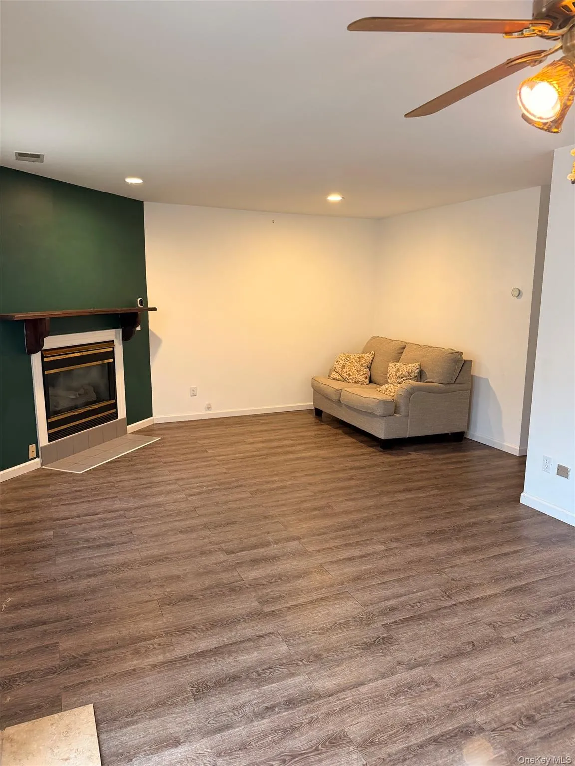 Living area with a ceiling fan, recessed lighting, wood finished floors, and a tiled fireplace Living area with a ceiling fan, recessed lighting, wood finished floors, and a tiled fireplace