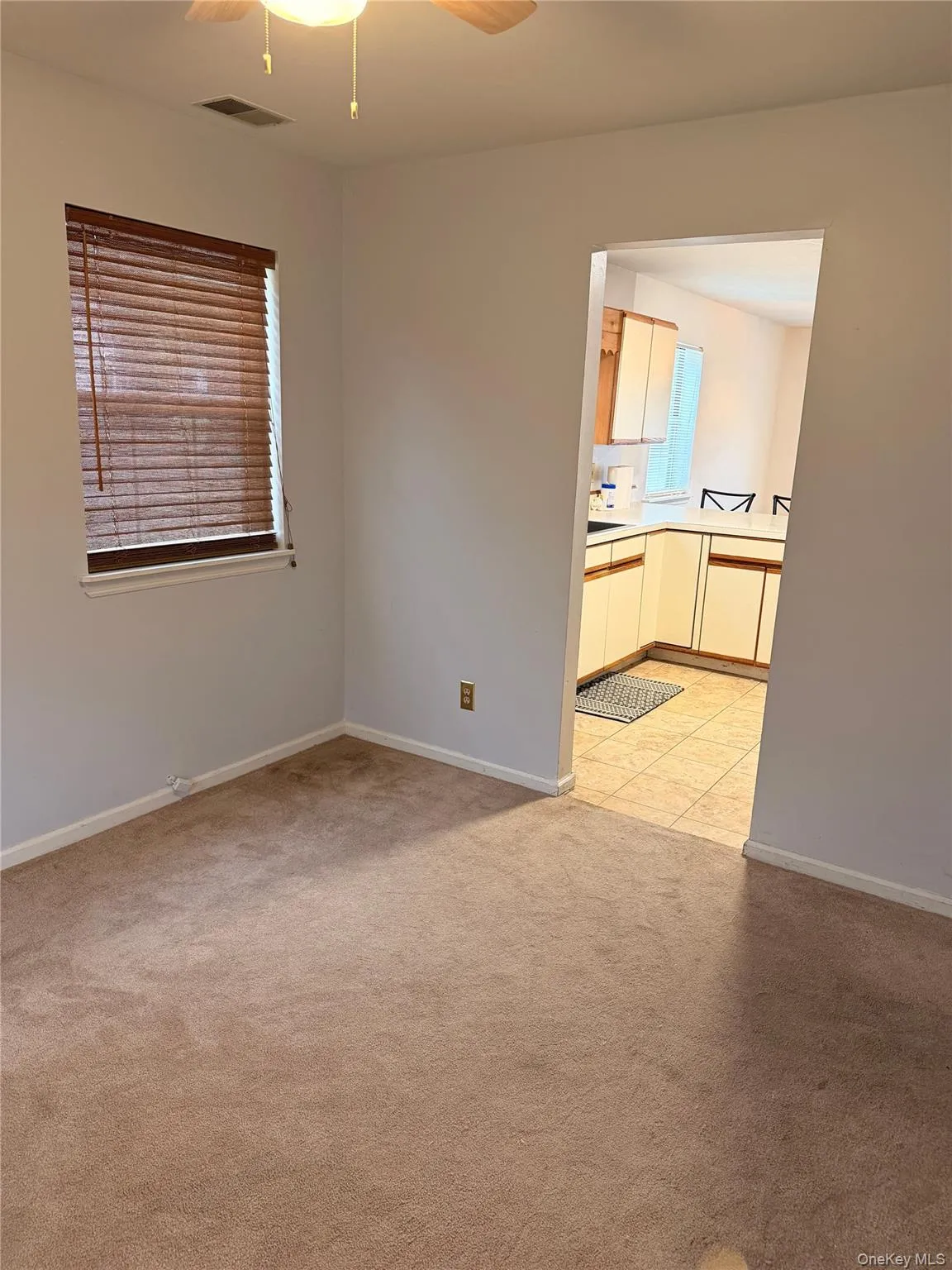 Empty room featuring light colored carpet, ceiling fan, and light tile patterned flooring Empty room featuring light colored carpet, ceiling fan, and light tile patterned flooring