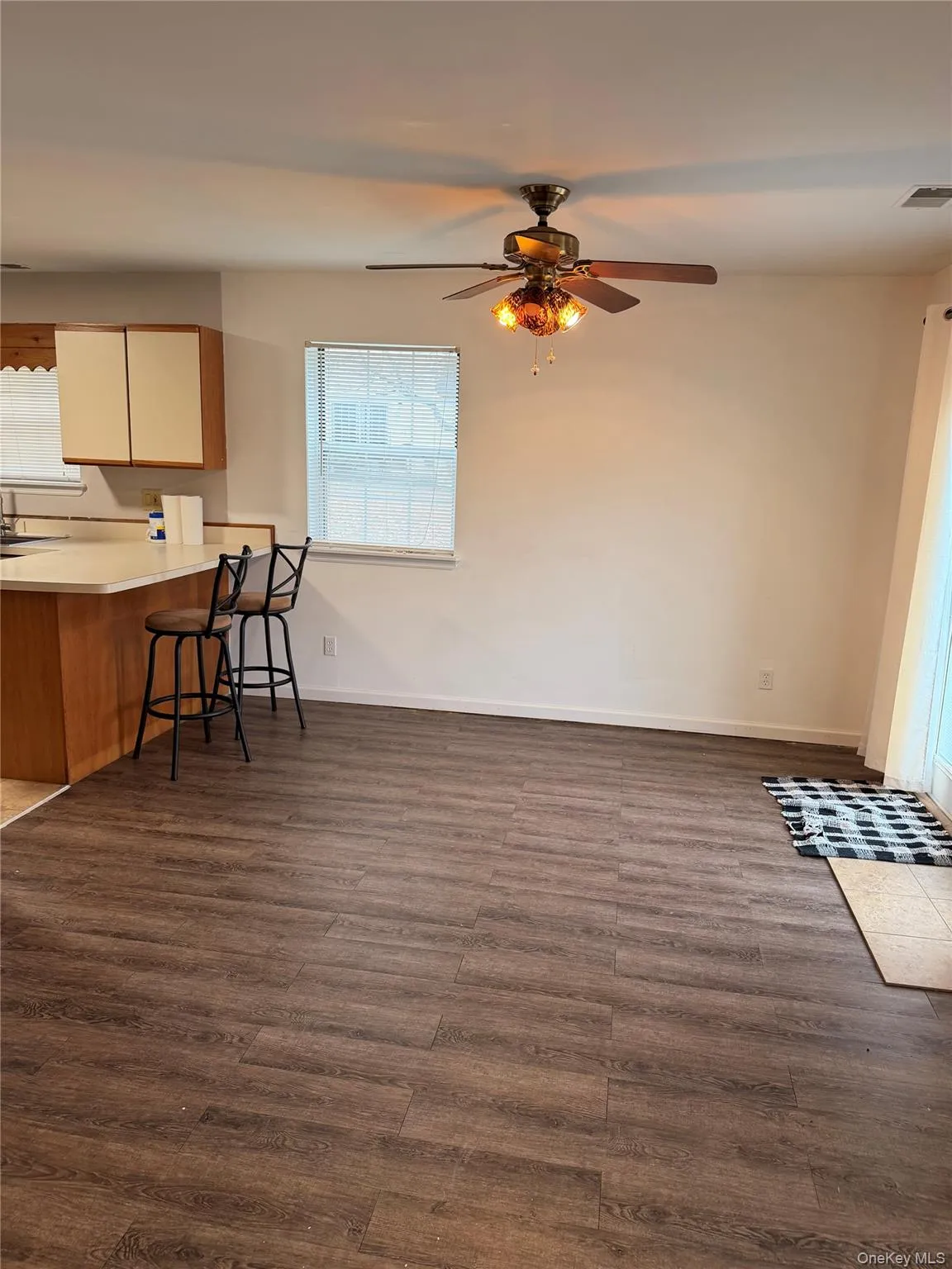 Kitchen featuring light countertops, brown cabinetry, a kitchen bar, and dark wood-type flooring Kitchen featuring light countertops, brown cabinetry, a kitchen bar, and dark wood-type flooring