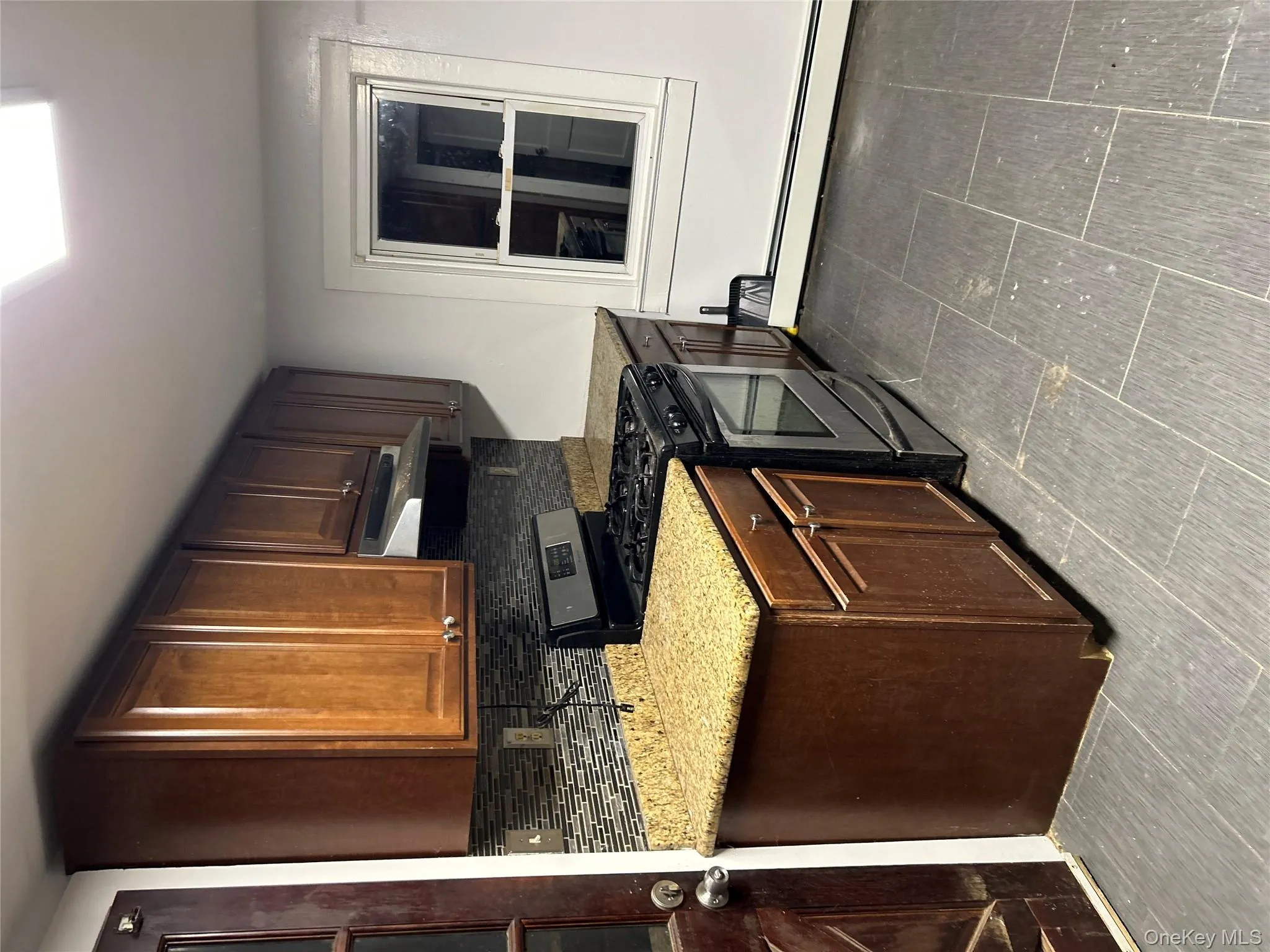Kitchen featuring stainless steel gas range oven, backsplash, a baseboard radiator, range hood, and light stone countertops Kitchen featuring stainless steel gas range oven, backsplash, a baseboard radiator, range hood, and light stone countertops