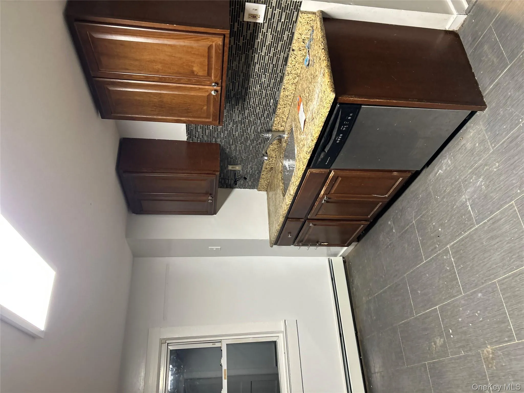 Kitchen with dark brown cabinetry, decorative backsplash, a baseboard radiator, and dishwashing machine Kitchen with dark brown cabinetry, decorative backsplash, a baseboard radiator, and dishwashing machine