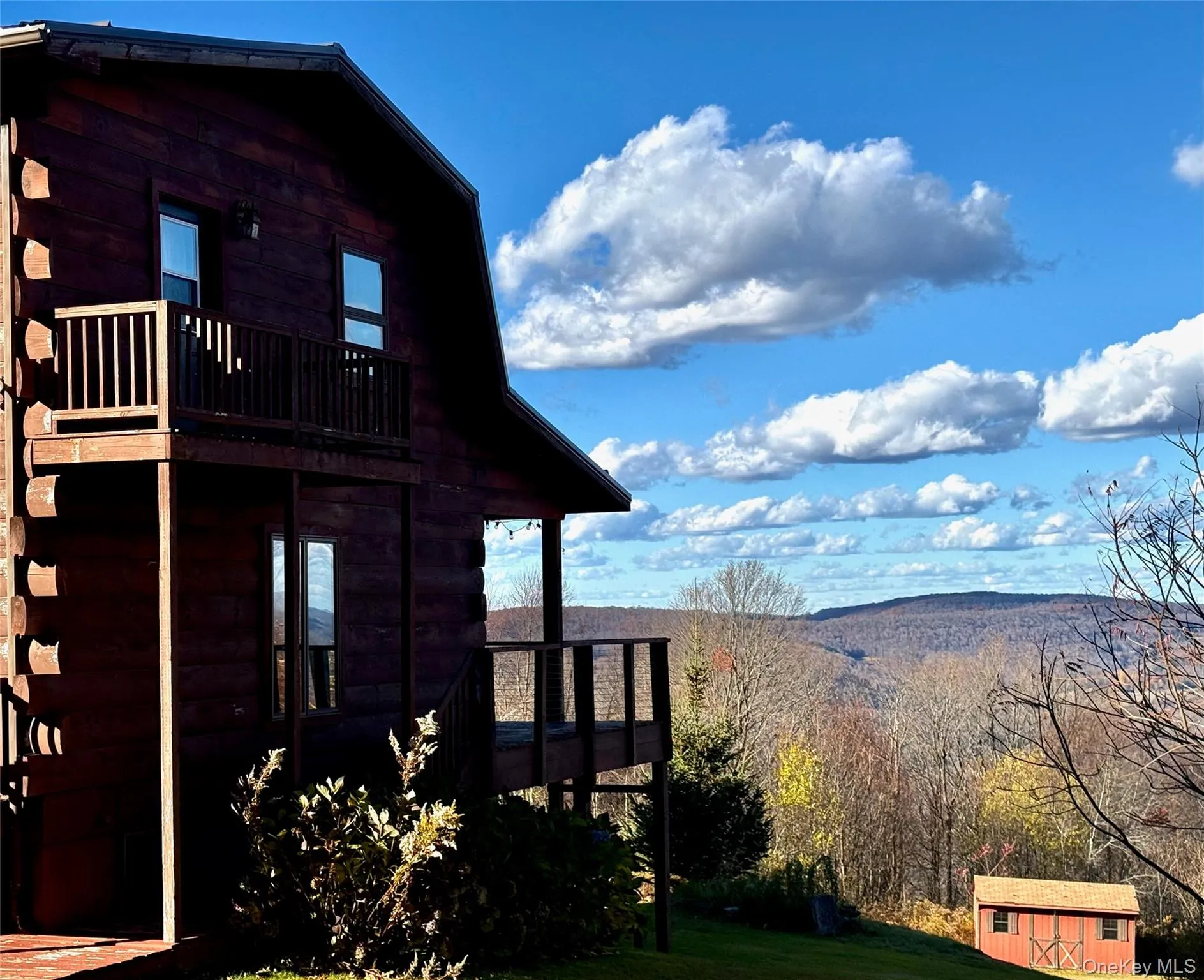 View of property exterior featuring a wooden deck, a storage shed, and a wooded view View of property exterior featuring a wooden deck, a storage shed, and a wooded view
