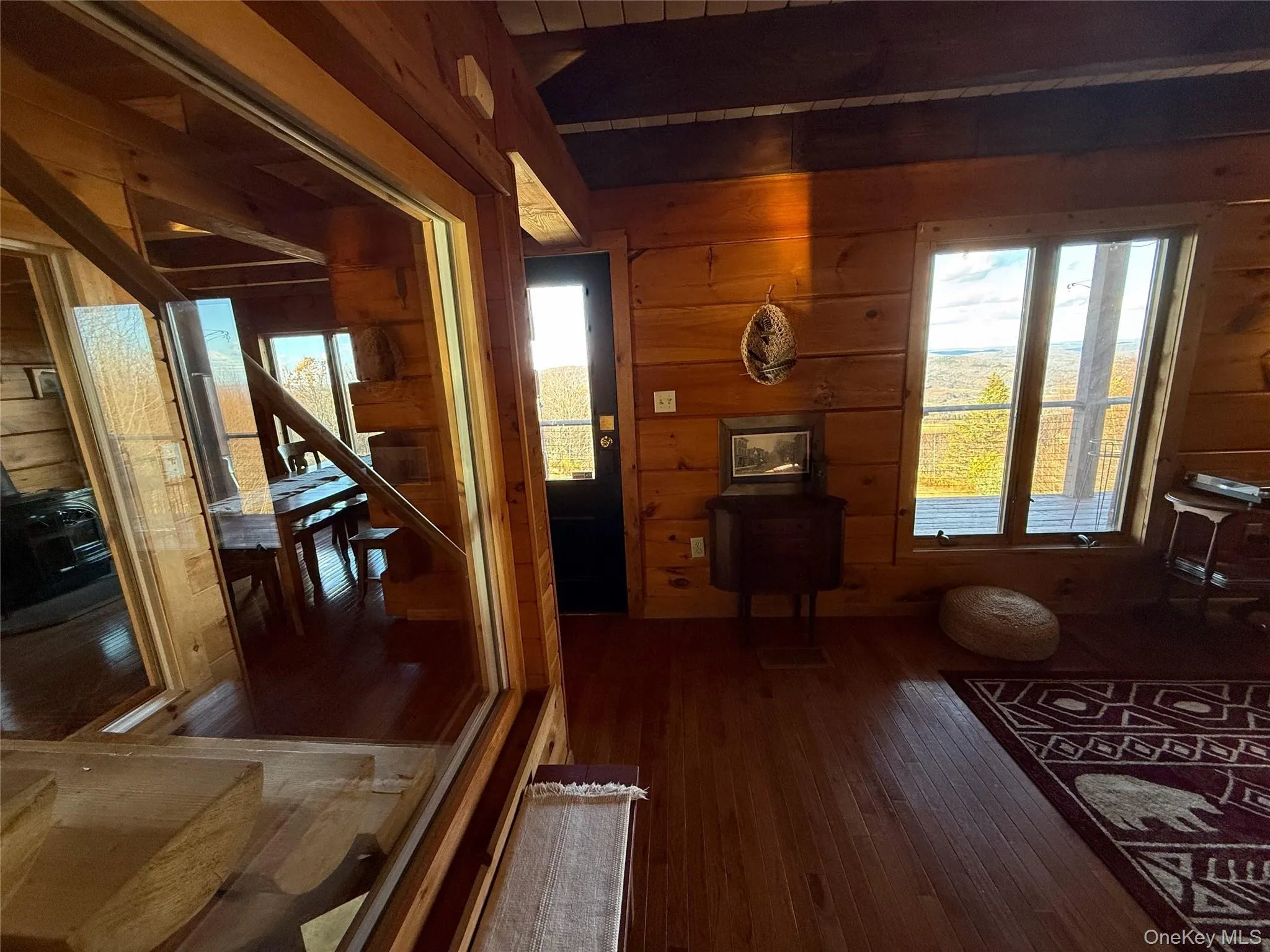 Living area with wooden walls, dark wood-style floors, and beamed ceiling Living area with wooden walls, dark wood-style floors, and beamed ceiling