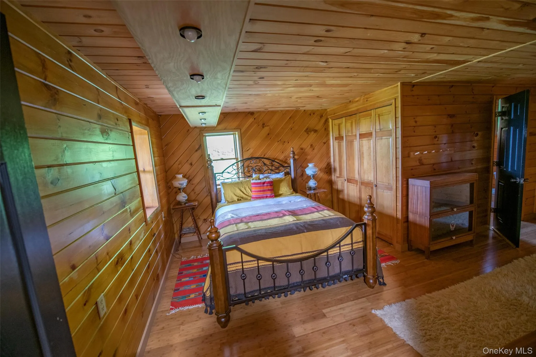 Bedroom featuring wood ceiling, wooden walls, and wood finished floors Bedroom featuring wood ceiling, wooden walls, and wood finished floors