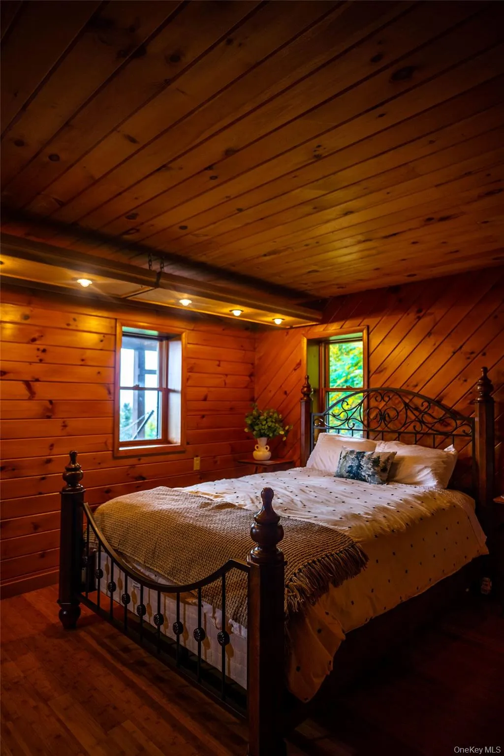 Bedroom featuring dark wood-type flooring, wooden ceiling, wooden walls, and multiple windows Bedroom featuring dark wood-type flooring, wooden ceiling, wooden walls, and multiple windows