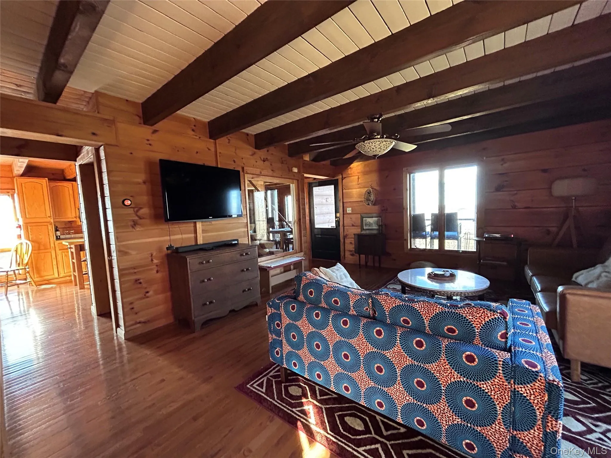 Bedroom with wooden walls, wood finished floors, and beam ceiling Bedroom with wooden walls, wood finished floors, and beam ceiling
